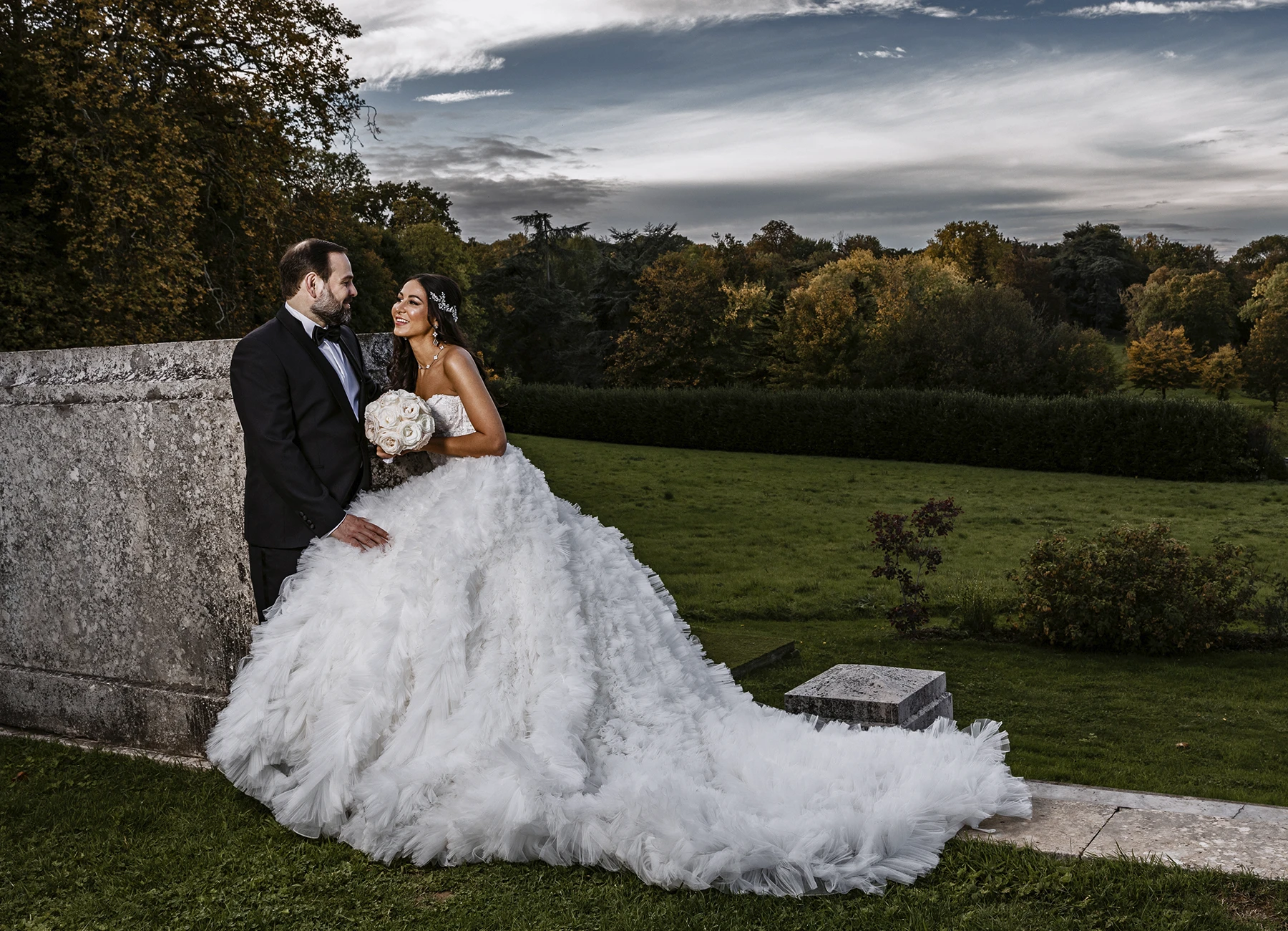 Mariés posant dans le parc du Château Bouffémont, profitant de la beauté du lieu pour leur séance photo. Photo par Laurène Zabary