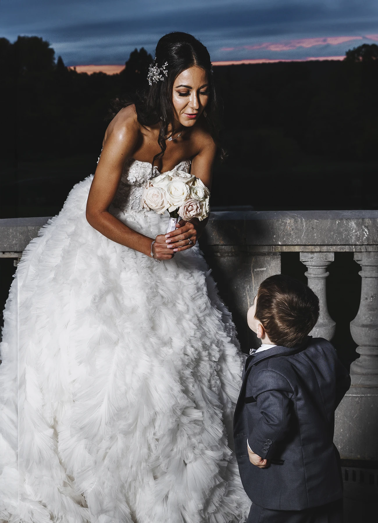 Scène nocturne où la mariée se penche vers un petit garçon lors de la réception au Château Bouffémont. Photo par Laurène Zabary.