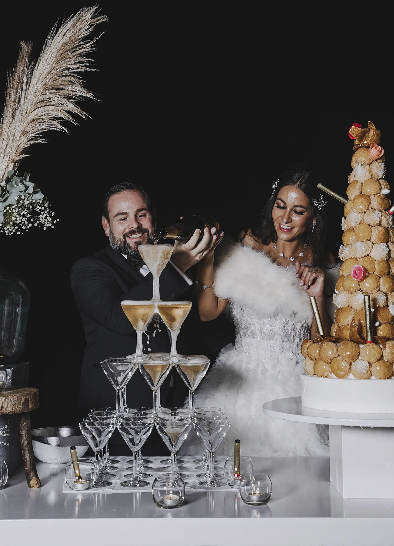 Les mariés versant du champagne dans une pyramide de verres lors de leur réception de mariage au Château Bouffémont. Photo par Laurène Zabary.