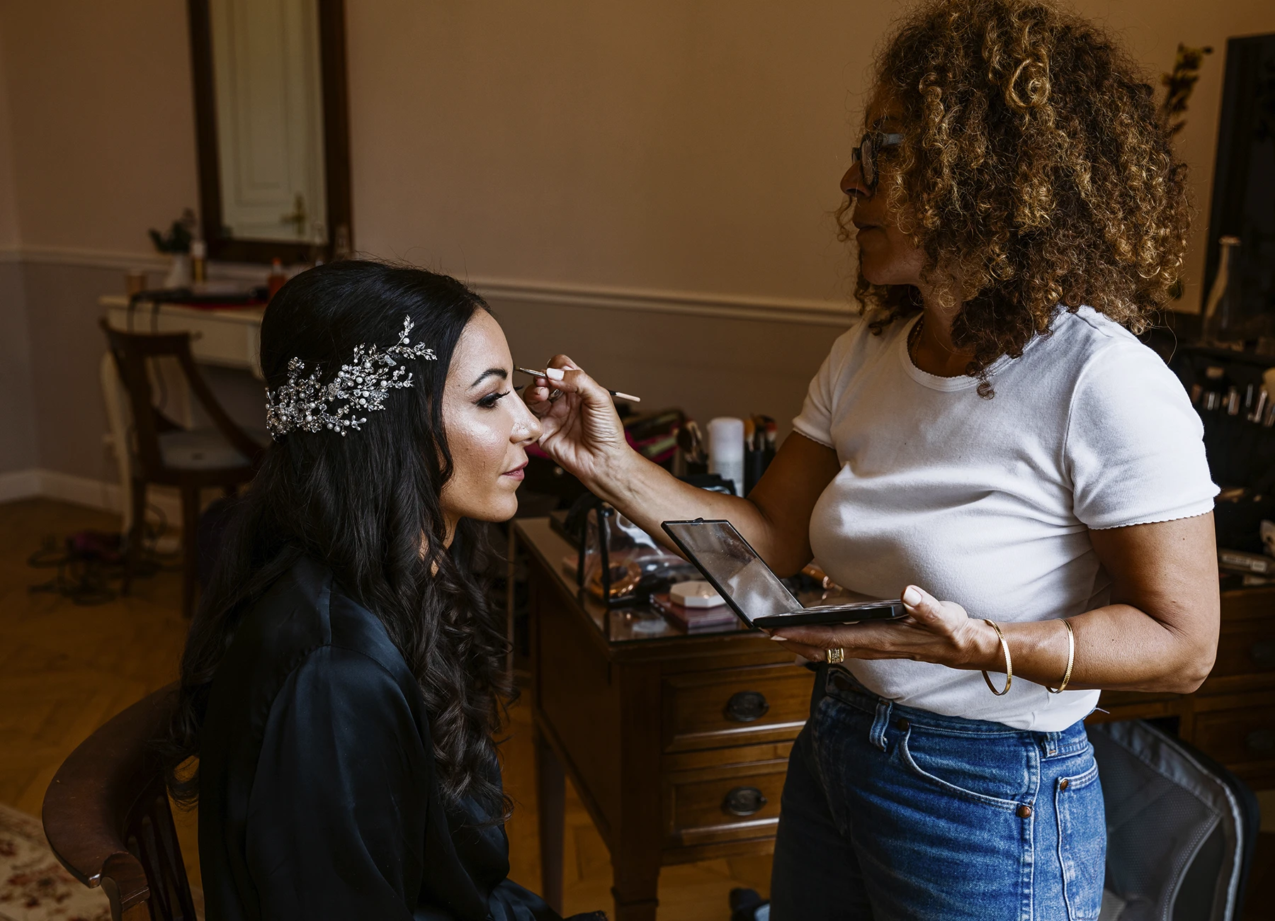Jeune femme brune, en train de se faire maquiller. Photo par Laurène Zabary