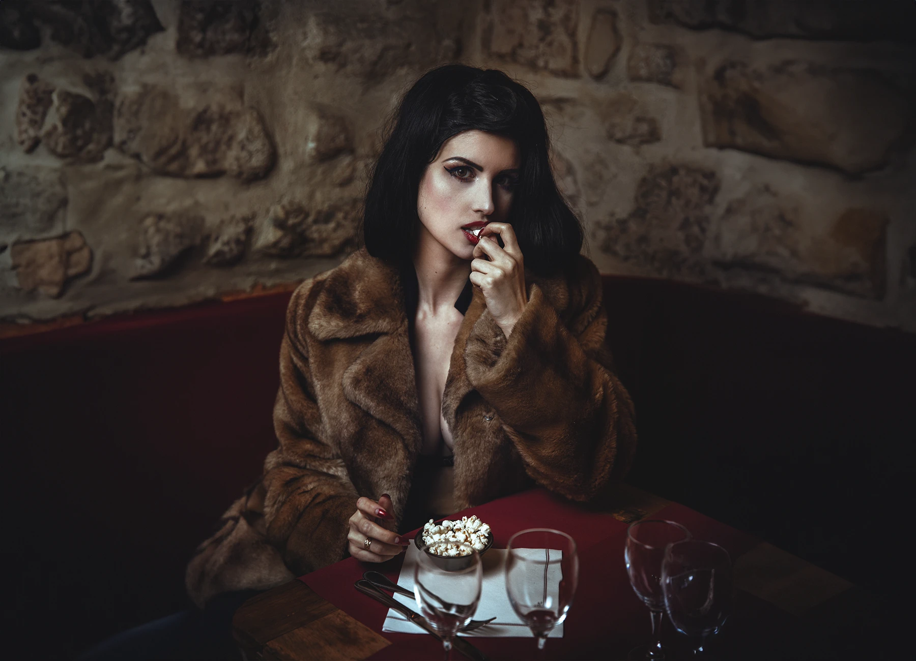 Elsa Oesinger, femme brune, portant un manteau en fourrure et mangeant du popcorn dans un restaurant parisien. Photo par Laurène Zabary