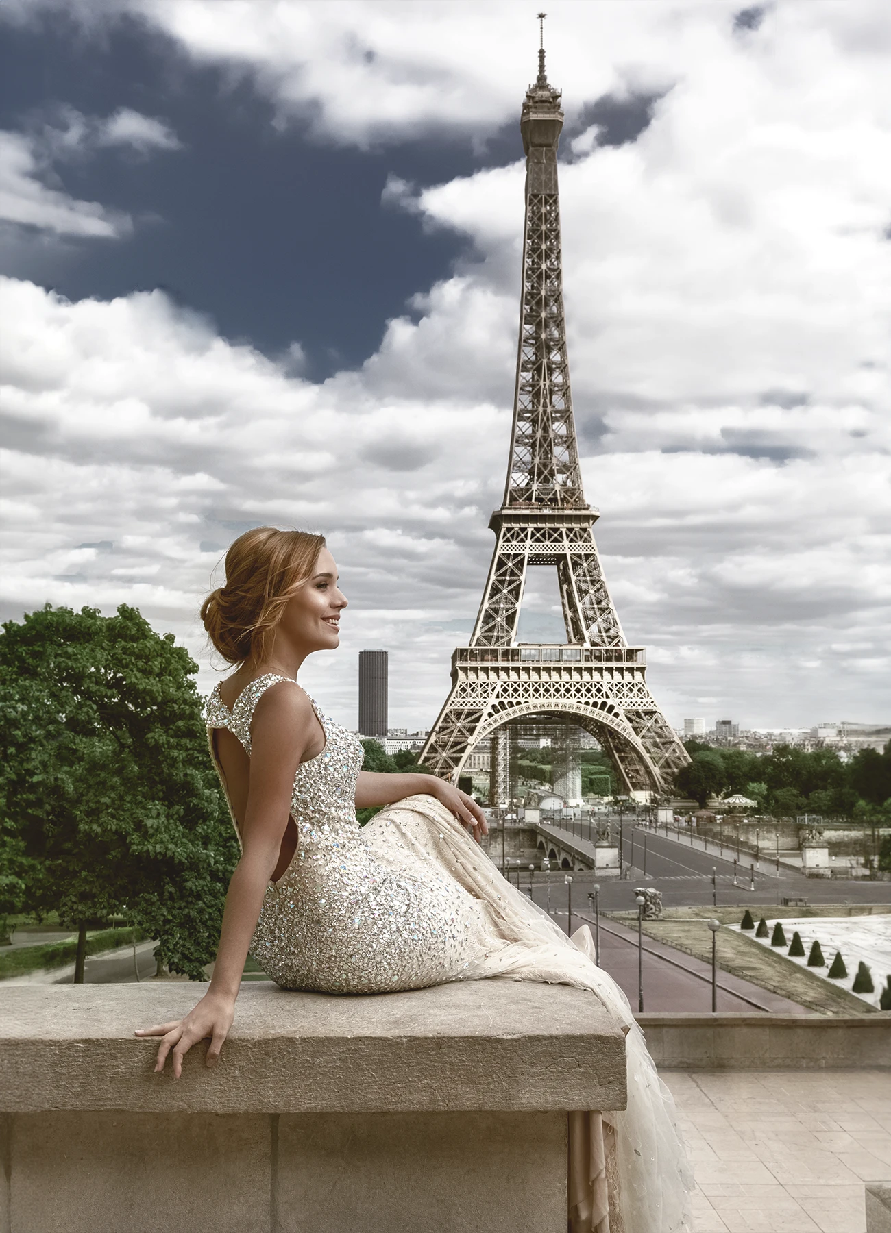 Ophélie Jaussaud, jeune femme blonde en robe de soirée couleur crème d'Elyssa Couture, assise face à la Tour Eiffel sur l'esplanade du Trocadéro. Photo par Laurène Zabary