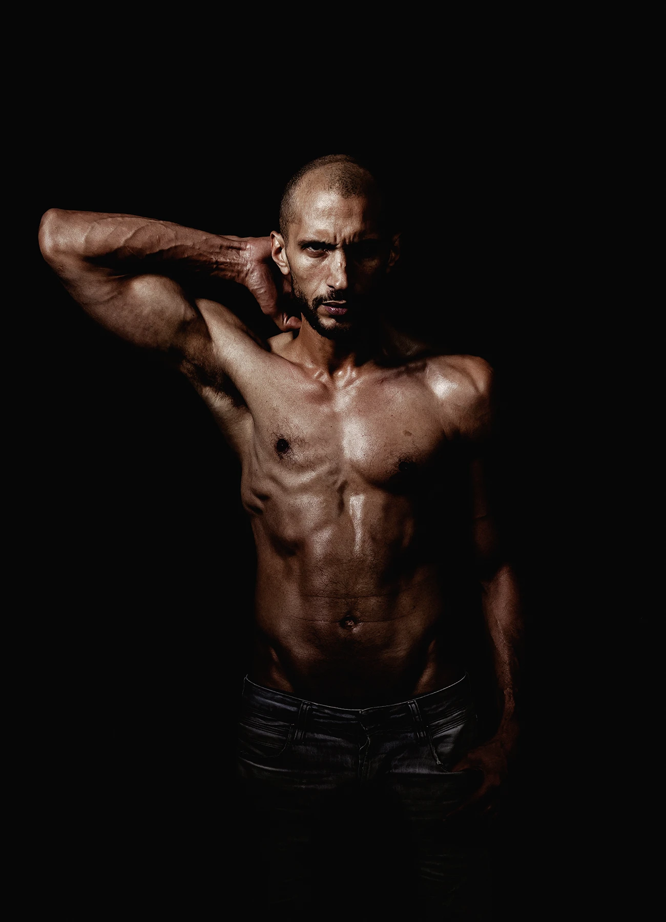 Portrait en noir et blanc d'un comédien fixant l'objectif avec intensité sur fond noir.