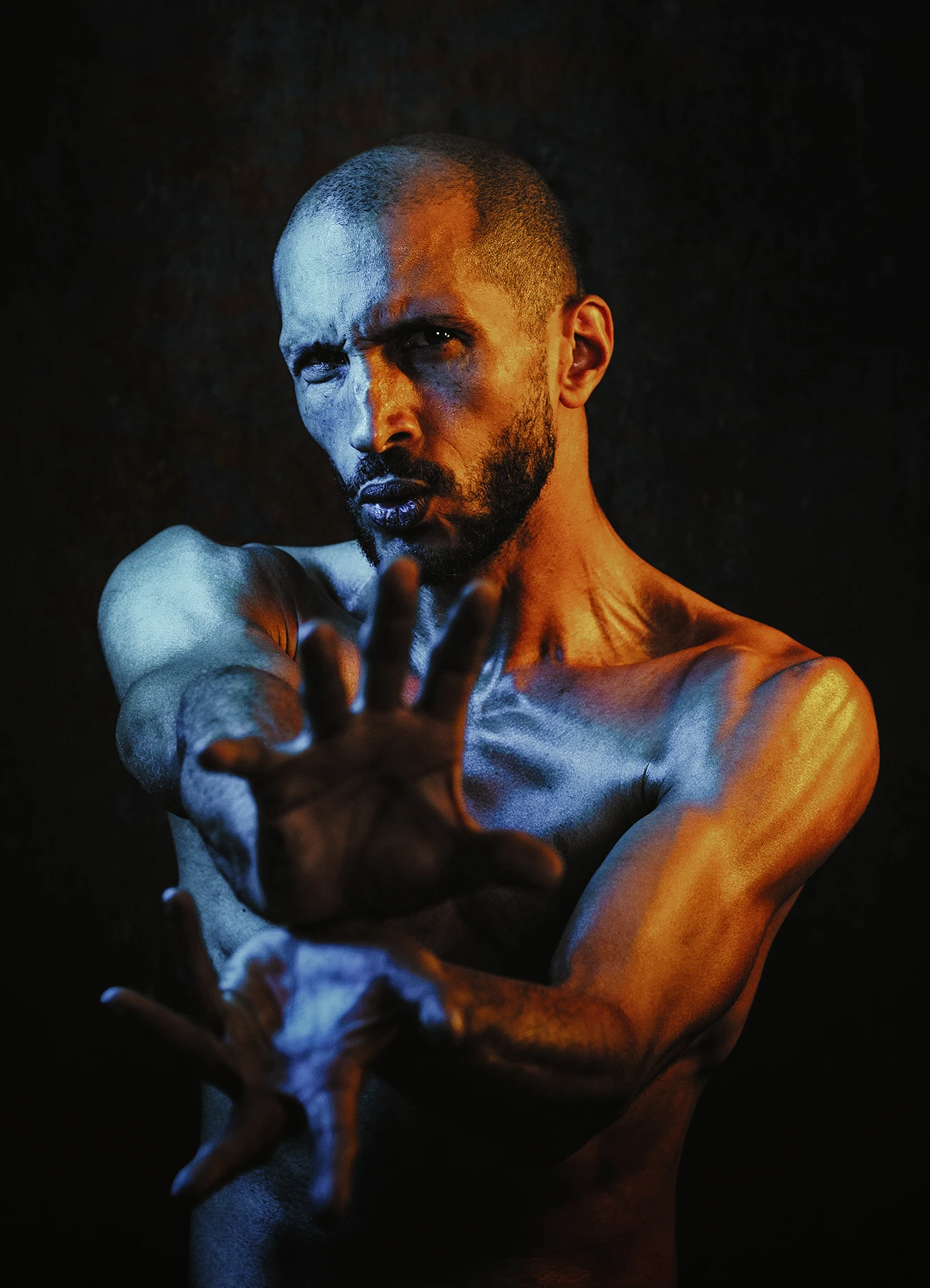 Mike mime un kamehameha, éclairé par des lumières jaunes et bleues sur fond noir.