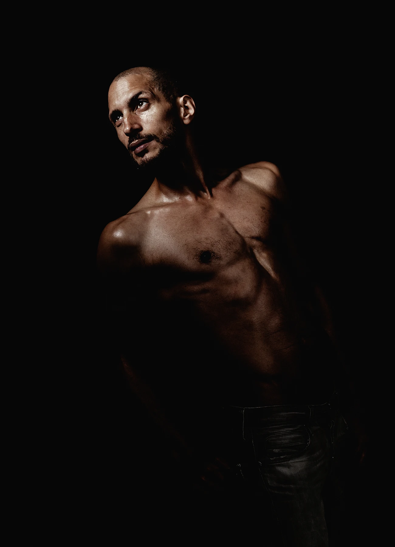 Portrait contrasté d’un comédien sur fond noir, regardant au loin avec intensité.