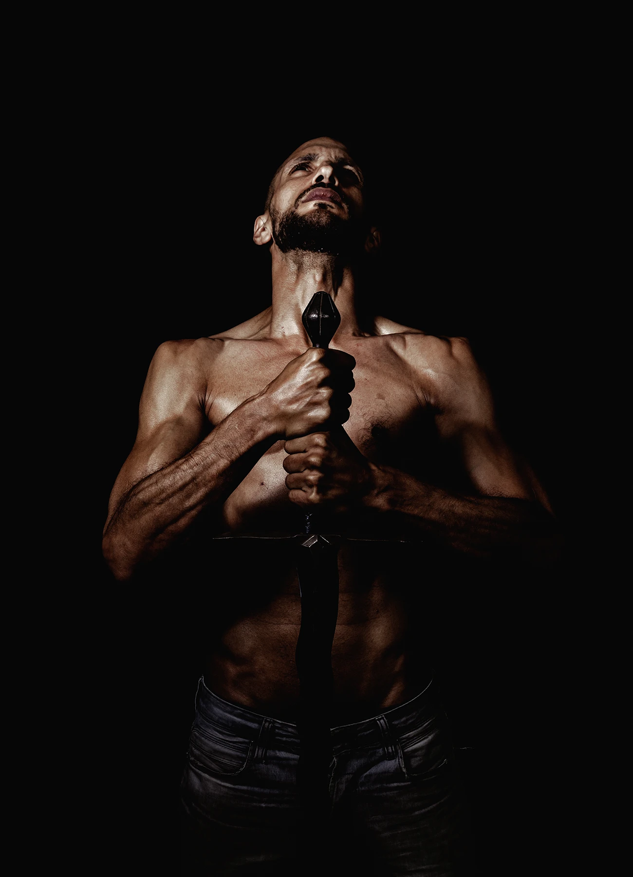 Portrait en clair-obscur d’un comédien regardant vers le ciel, tenant son épée à deux mains.