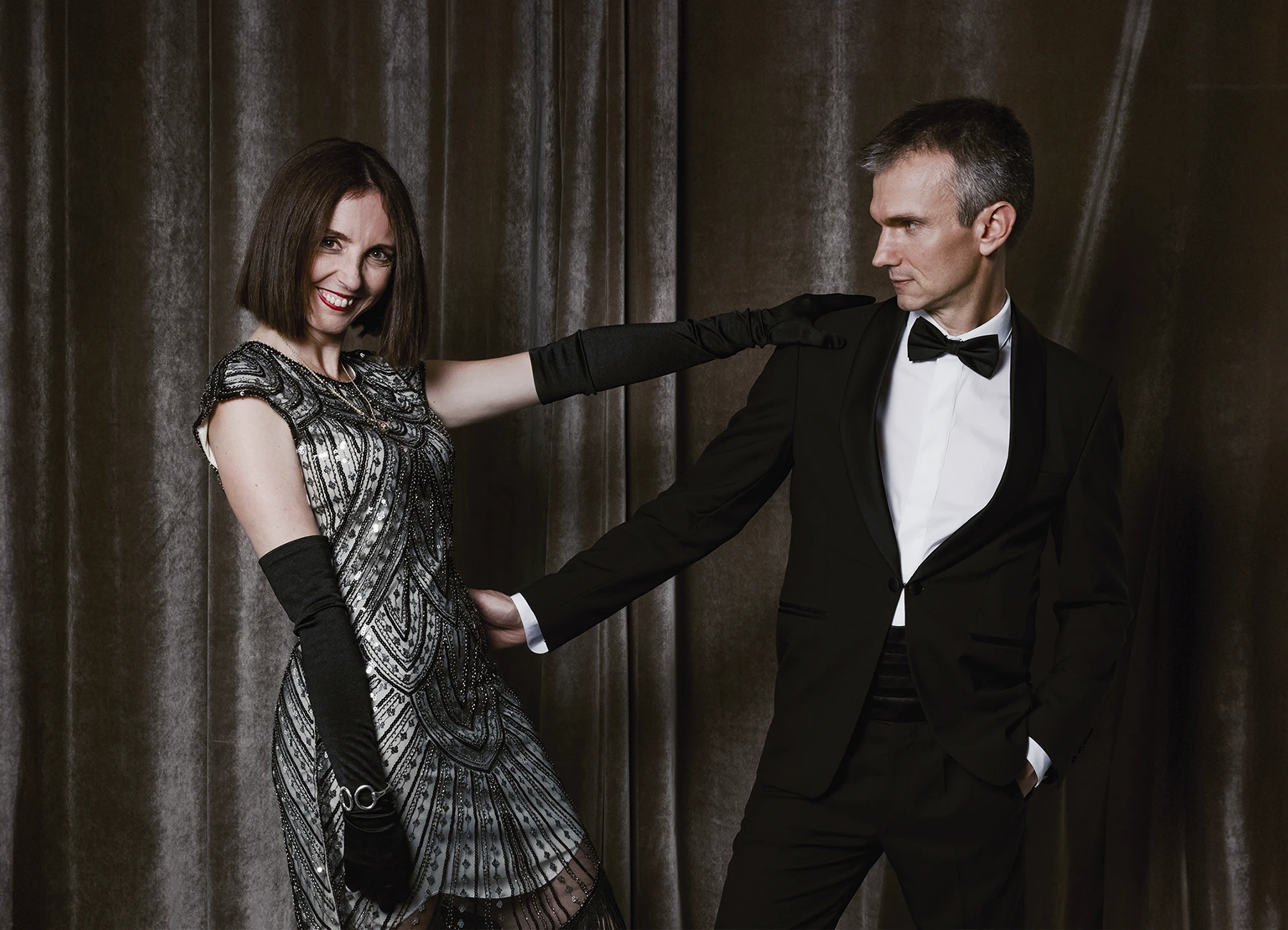 Portrait d’un couple prêt à danser le tango, posant devant une draperie, réalisé lors d’une soirée d’anniversaire sur le thème des années 20 à l’hôtel Vernet par Laurène Zabary.