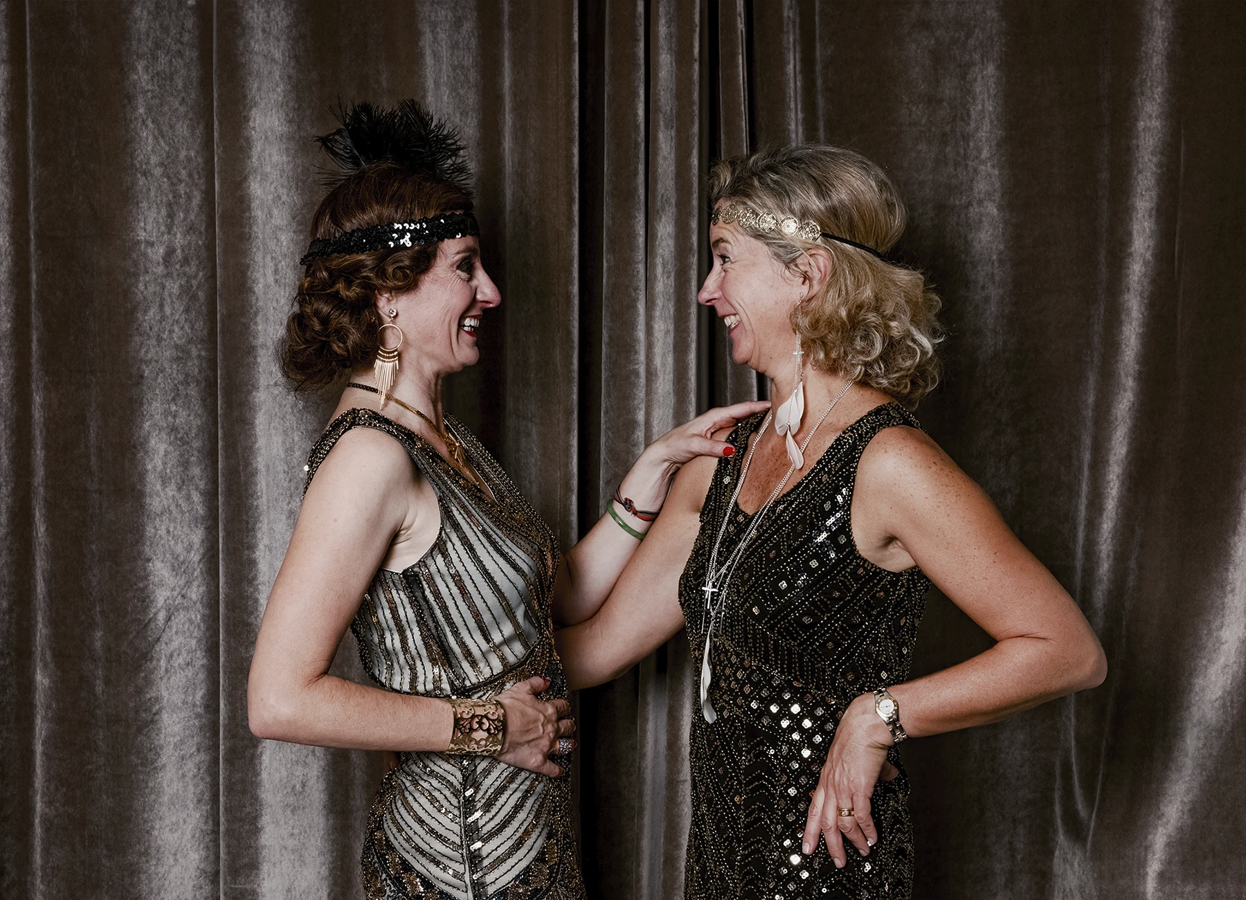 Portrait de deux femmes riant en se regardant devant une draperie, réalisé lors d’une soirée d’anniversaire sur le thème des années 20 à l’hôtel Vernet par Laurène Zabary.