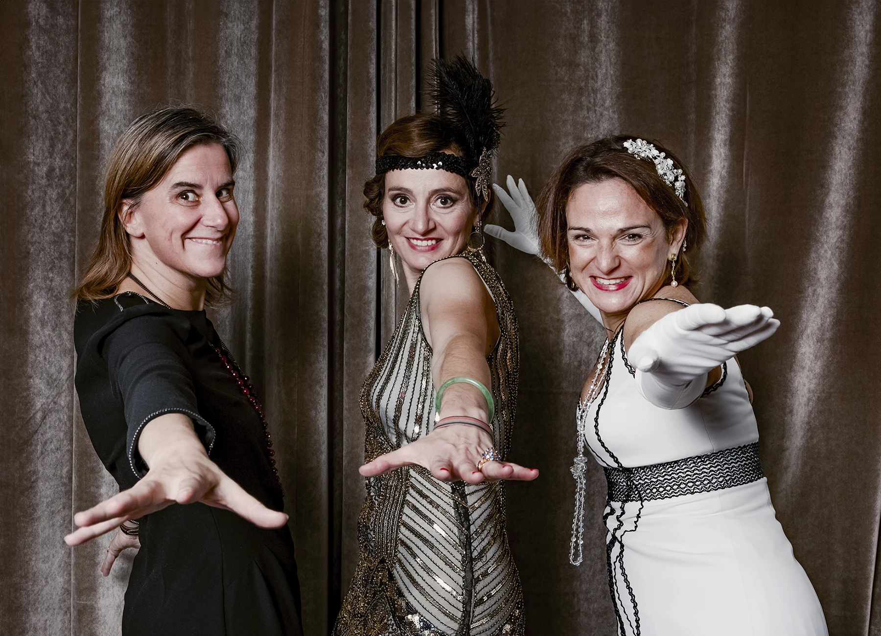 Portrait de trois femmes souriantes tendant la main vers l’objectif, posant devant une draperie, réalisé lors d’une soirée d’anniversaire sur le thème des années 20 à l’hôtel Vernet par Laurène Zabary.