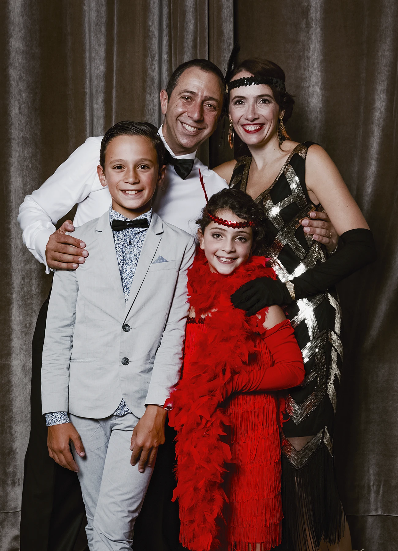 Portrait d’un couple avec leurs deux enfants posant devant une draperie, réalisé lors d’une soirée d’anniversaire sur le thème des années 20 à l’hôtel Vernet par Laurène Zabary.