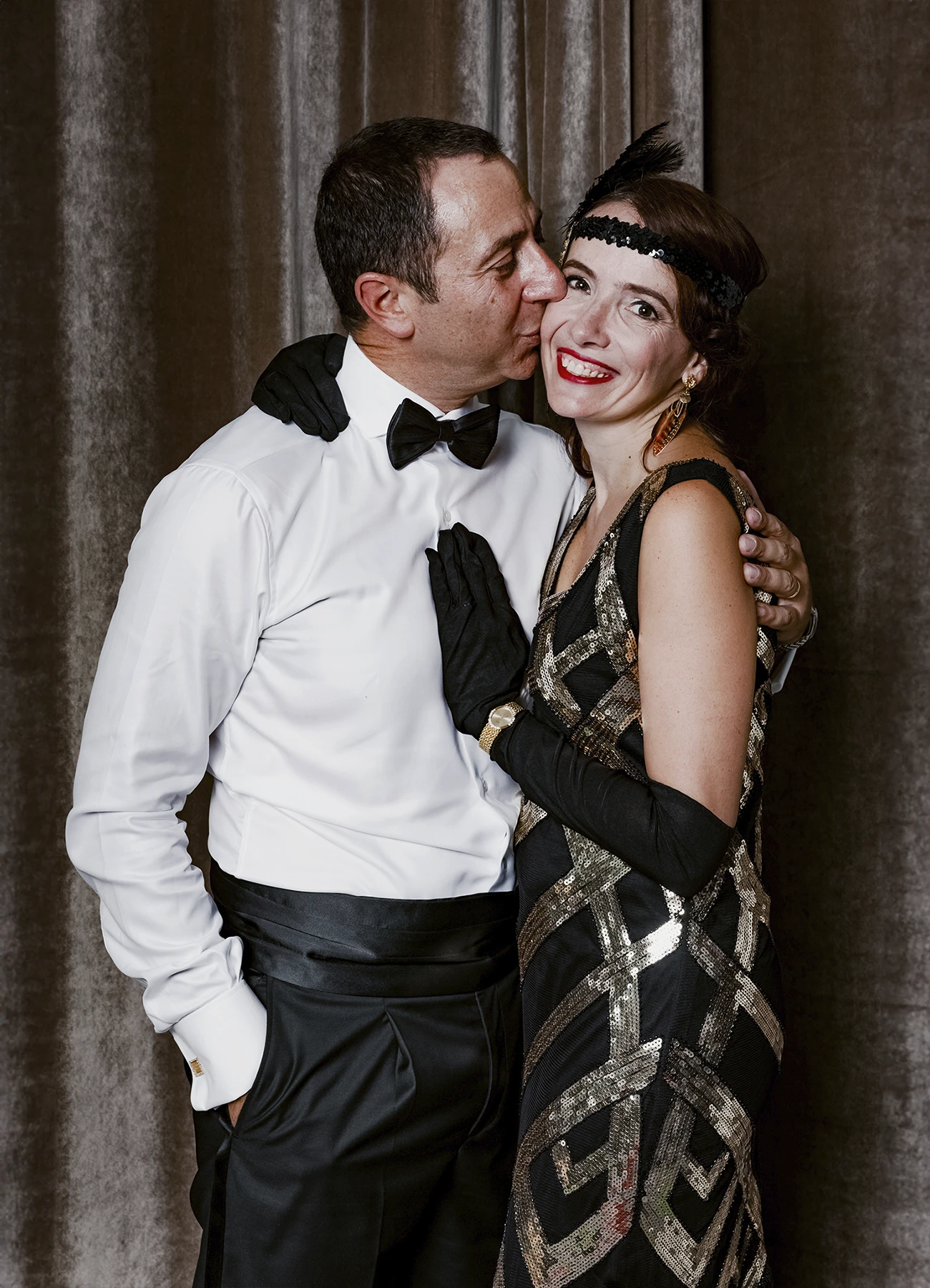 Portrait d’un homme embrassant sa femme sur la joue devant une draperie, réalisé lors d’une soirée d’anniversaire sur le thème des années 20 à l’hôtel Vernet par Laurène Zabary.