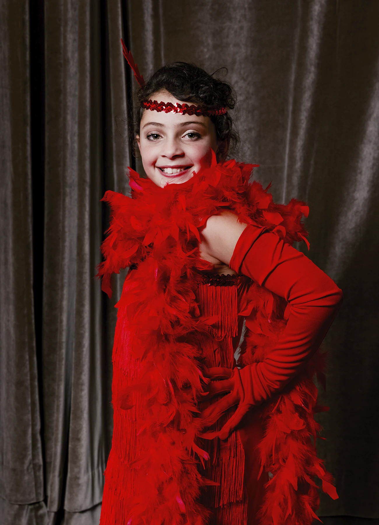 Portrait d’une petite fille en tenue rouge posant devant une draperie, réalisé lors d’une soirée d’anniversaire à l’hôtel Vernet par Laurène Zabary.