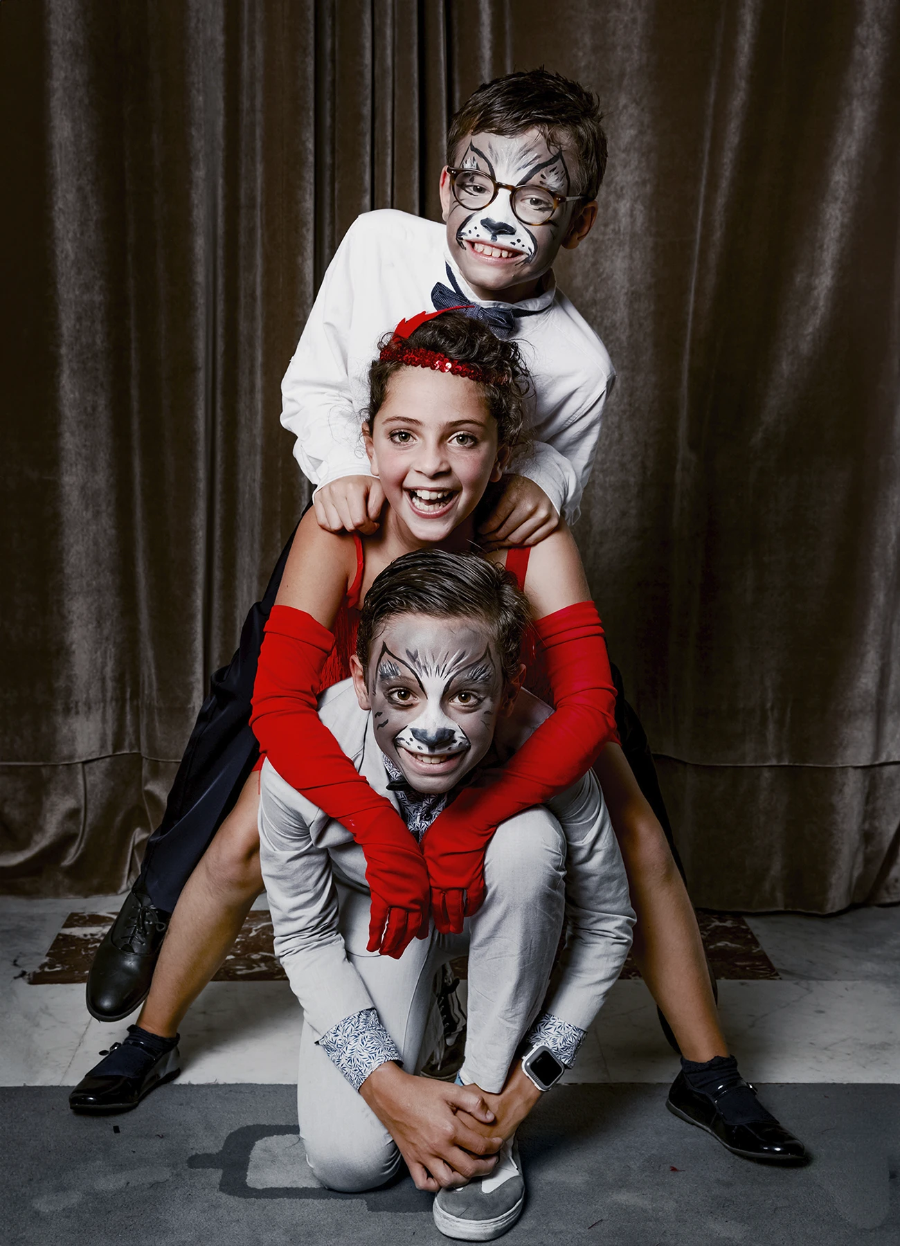Portrait de deux petits garçons maquillés en loups et d’une petite fille posant devant une draperie, réalisé lors d’une soirée d’anniversaire sur le thème des années 20 à l’hôtel Vernet par Laurène Zabary.