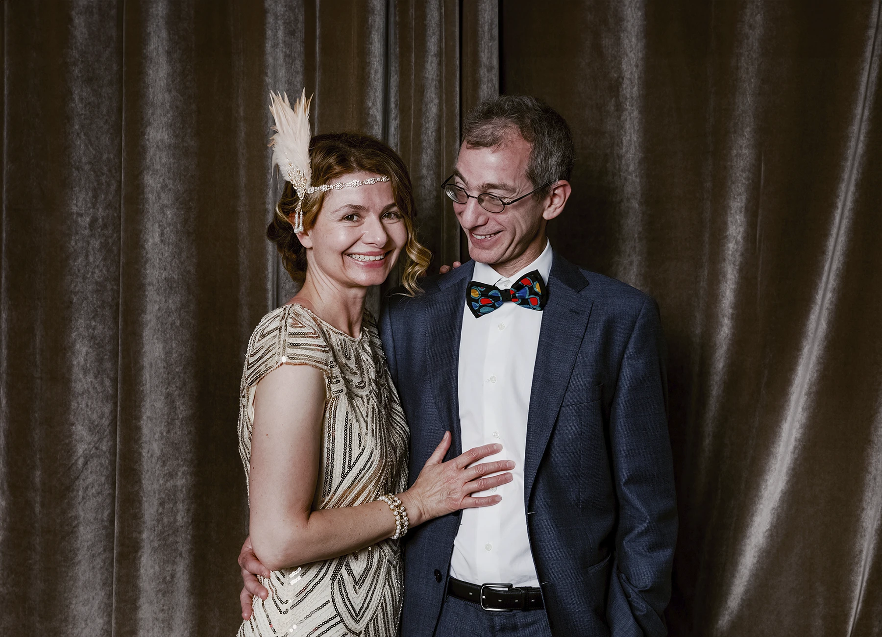Portrait d’un homme et d’une femme riant devant une draperie, réalisé lors d’une soirée d’anniversaire sur le thème des années 20 à l’hôtel Vernet par Laurène Zabary.