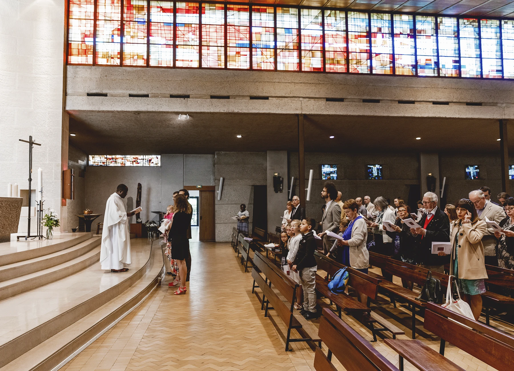 La famille chante ensemble dans l’église Saint-Joseph de Montrouge durant la cérémonie de baptême, capturée par Laurène Zabary.