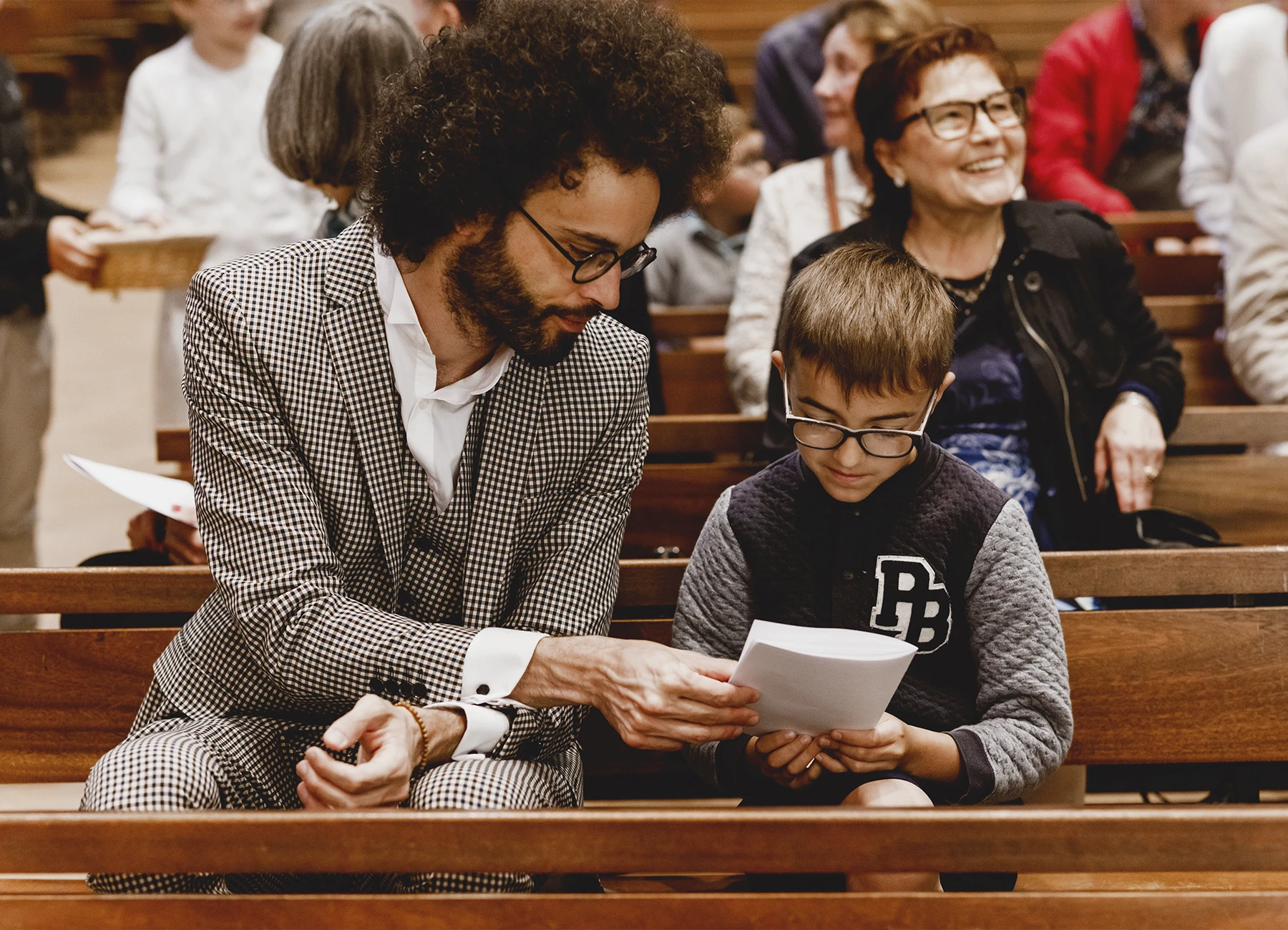 Un père et son fils assis sur un banc de l’église Saint-Joseph de Montrouge durant une cérémonie de baptême, photographiés par Laurène Zabary.