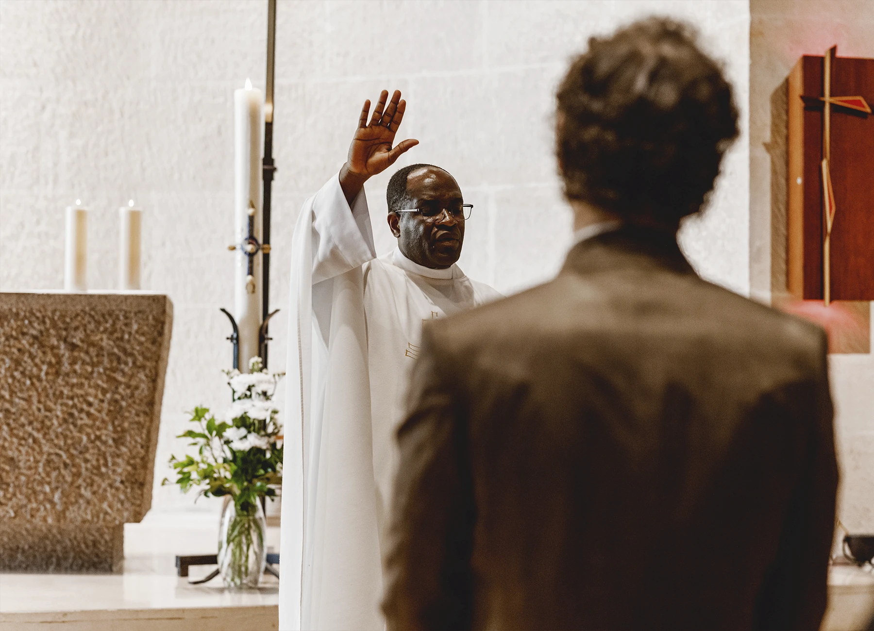 Le prêtre officie pendant la cérémonie de baptême à l’église Saint-Joseph de Montrouge, capturé par Laurène Zabary.