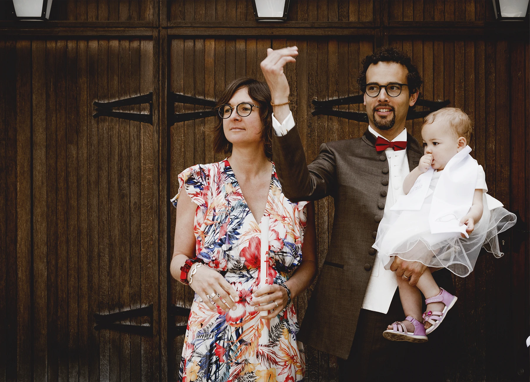 Le couple et le bébé devant l’entrée de l’église Saint-Joseph de Montrouge, le père faisant signe à quelqu’un de venir poser, capturé par Laurène Zabary.