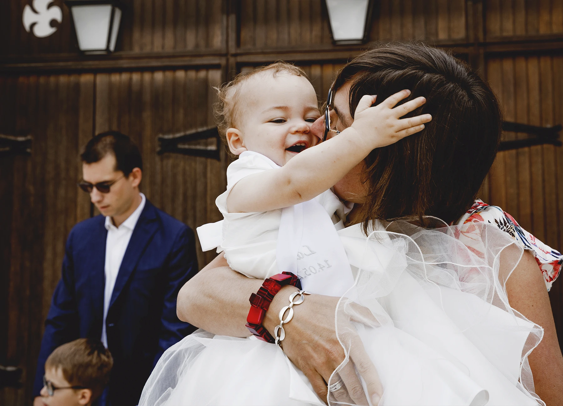 Le bébé dans les bras de sa mère qui l’embrasse tendrement, capturé lors d’un baptême à l’église Saint-Joseph de Montrouge par Laurène Zabary.