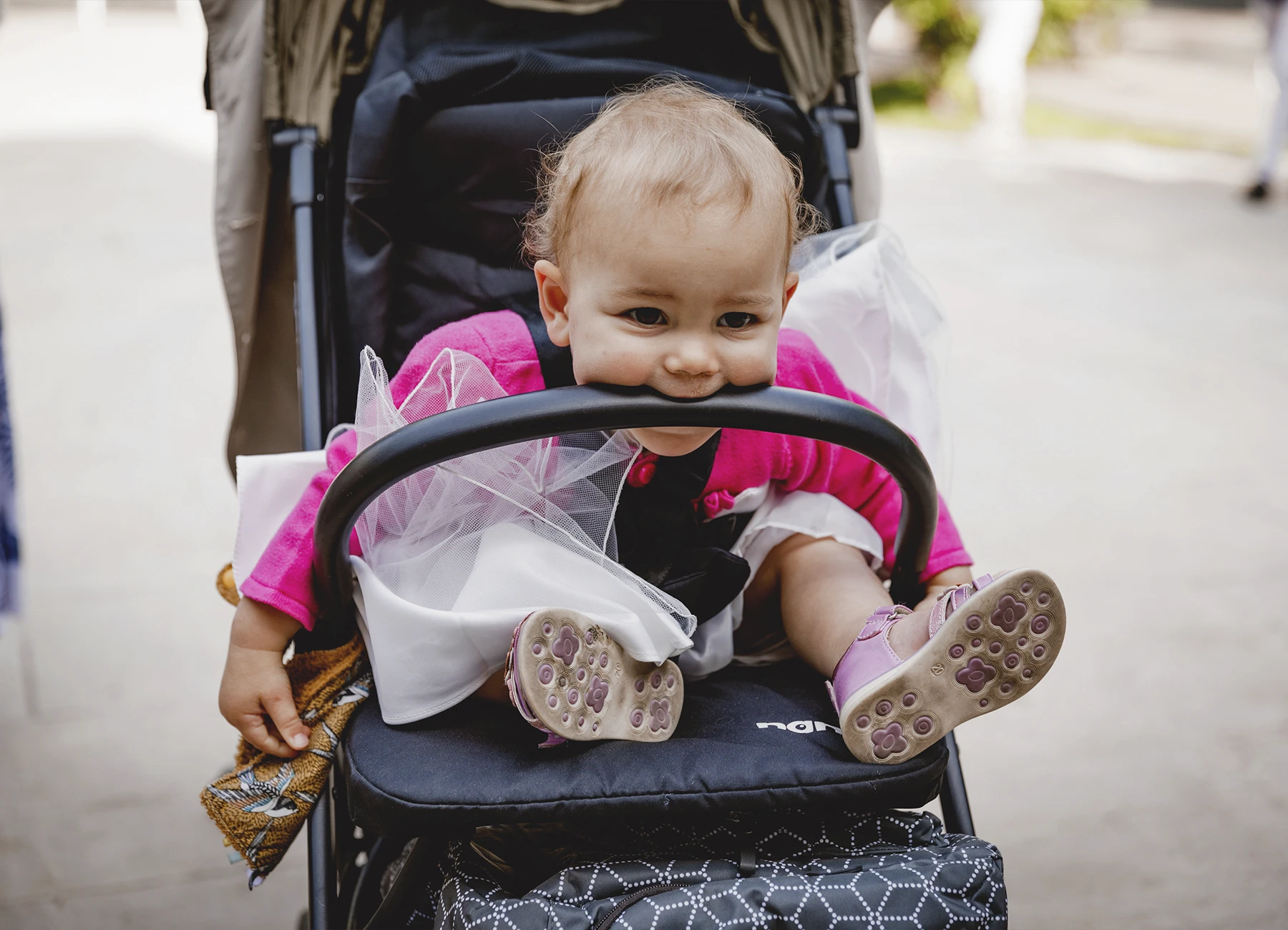 Le bébé dans sa poussette, mordant l’arceau, à l’extérieur de l’église Saint-Joseph de Montrouge après la cérémonie, photographié par Laurène Zabary.