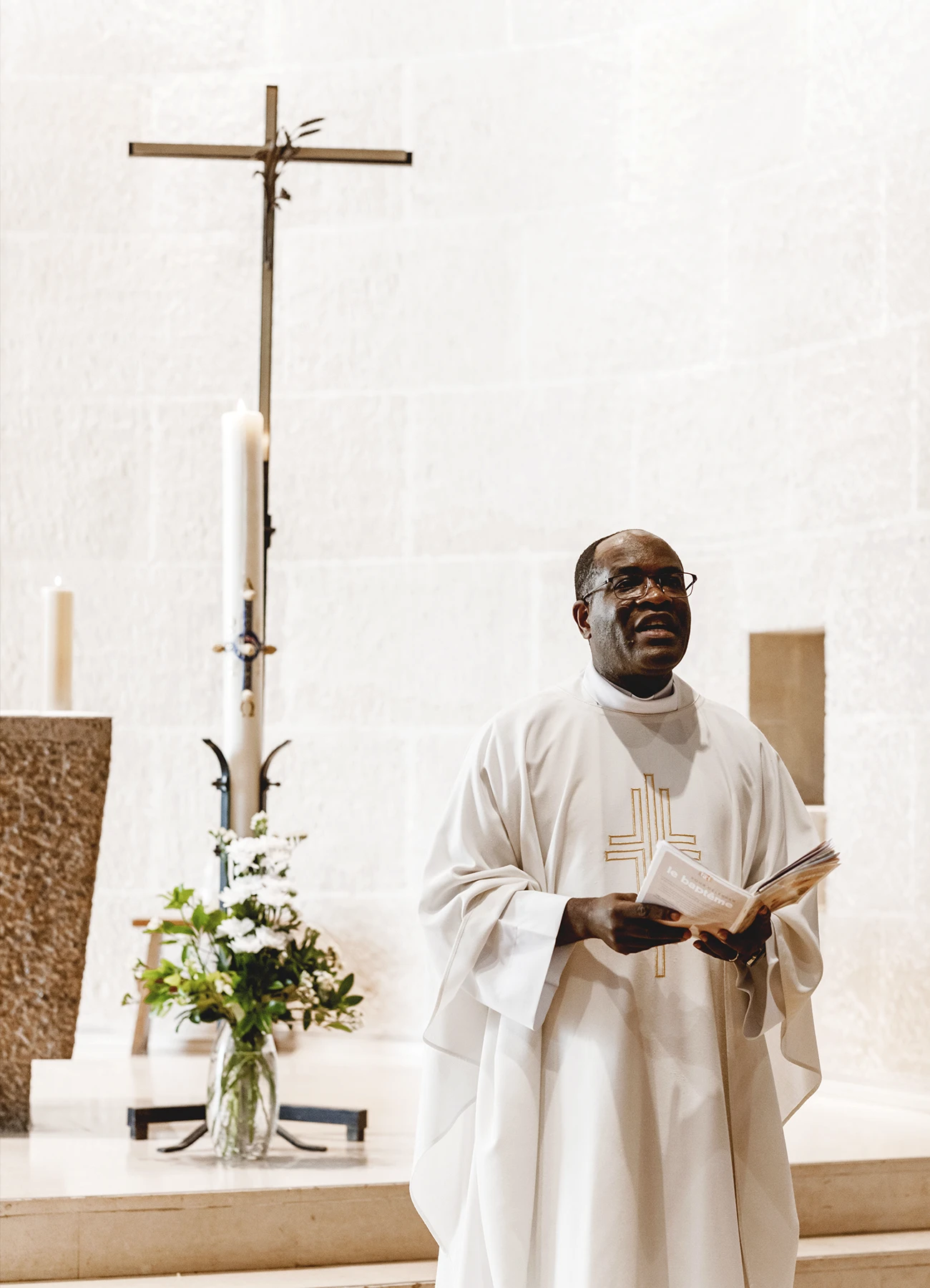 Le prêtre près de l'autel lors d’un baptême à l’église Saint-Joseph de Montrouge, photographié par Laurène Zabary.