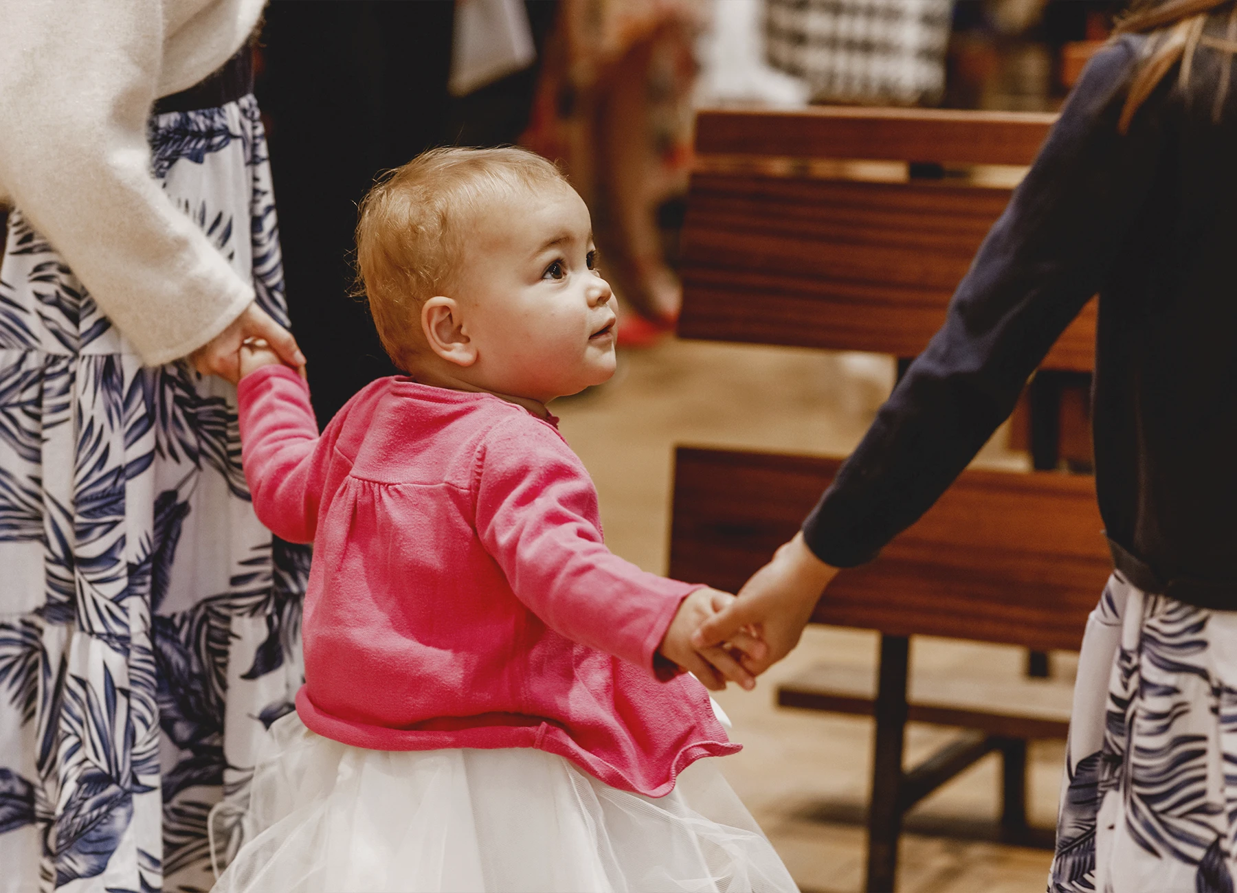 Le bébé et les enfants de la famille se tiennent par la main dans l’église Saint-Joseph de Montrouge avant la cérémonie de baptême, immortalisés par Laurène Zabary.