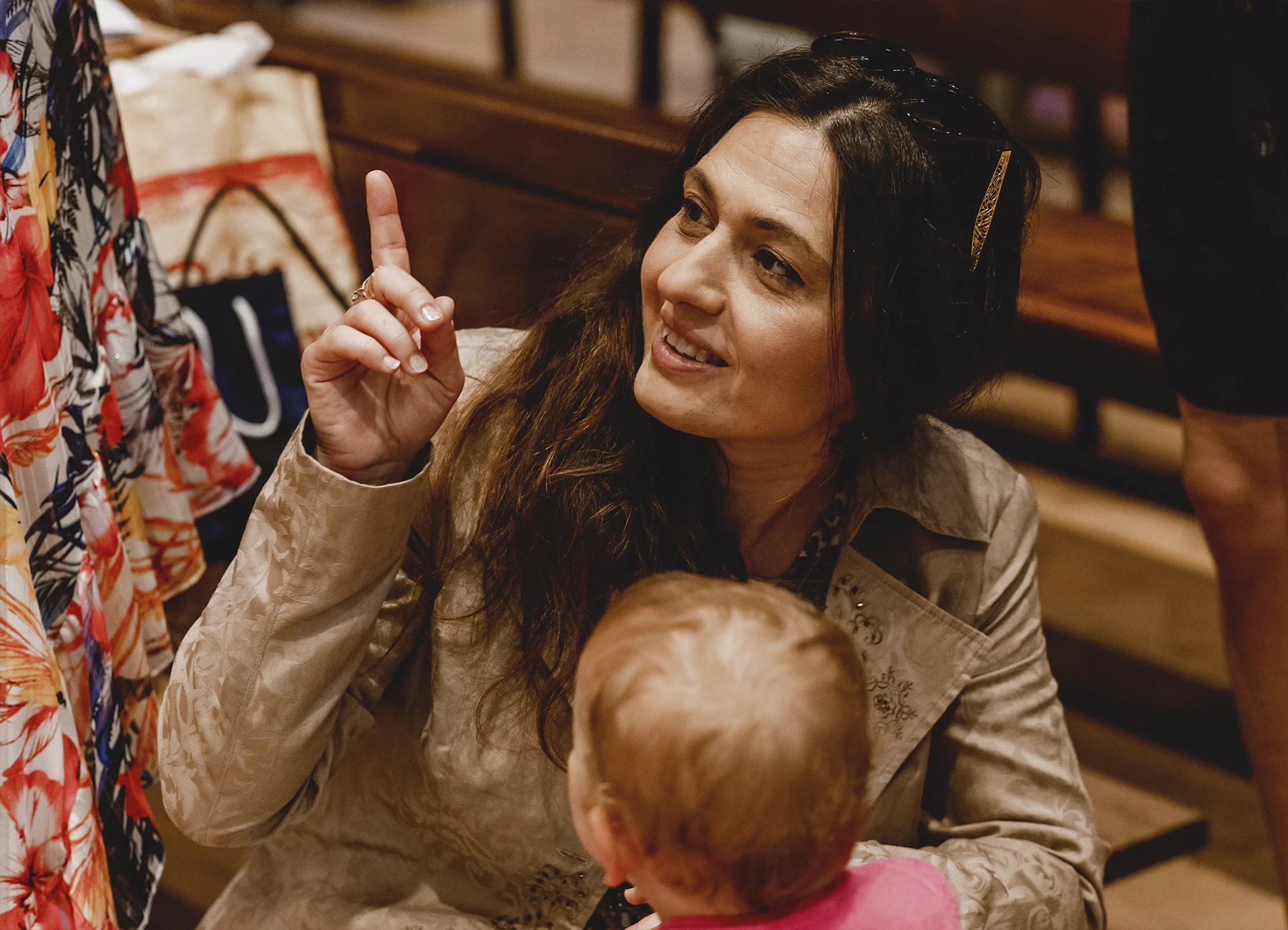 Une membre de la famille parle tendrement au bébé à baptiser dans l’église Saint-Joseph de Montrouge avant la cérémonie, photographiée par Laurène Zabary.