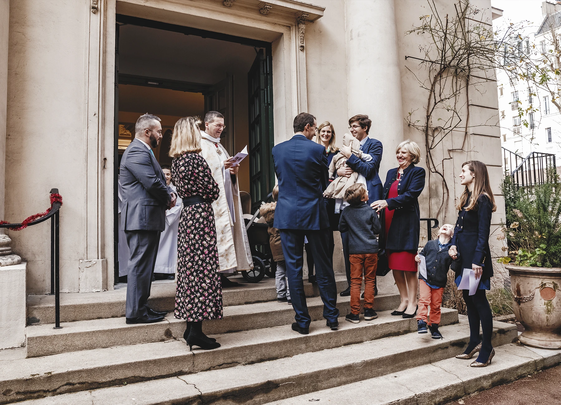 Les parents et le prêtre accueillant les invités à l’entrée de l’église