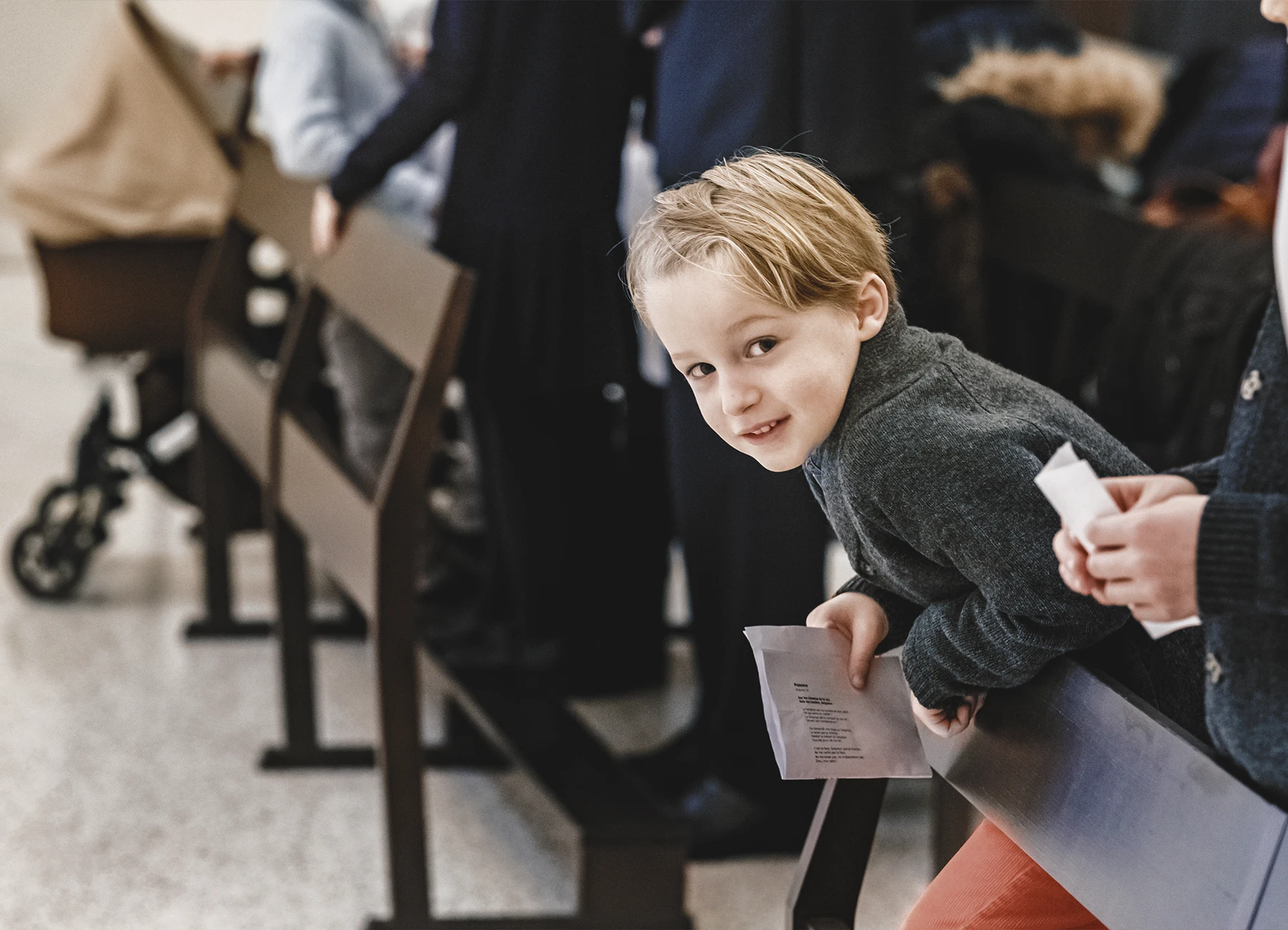 Un petit garçon tenant un papier sur lequel est inscrite une prière.