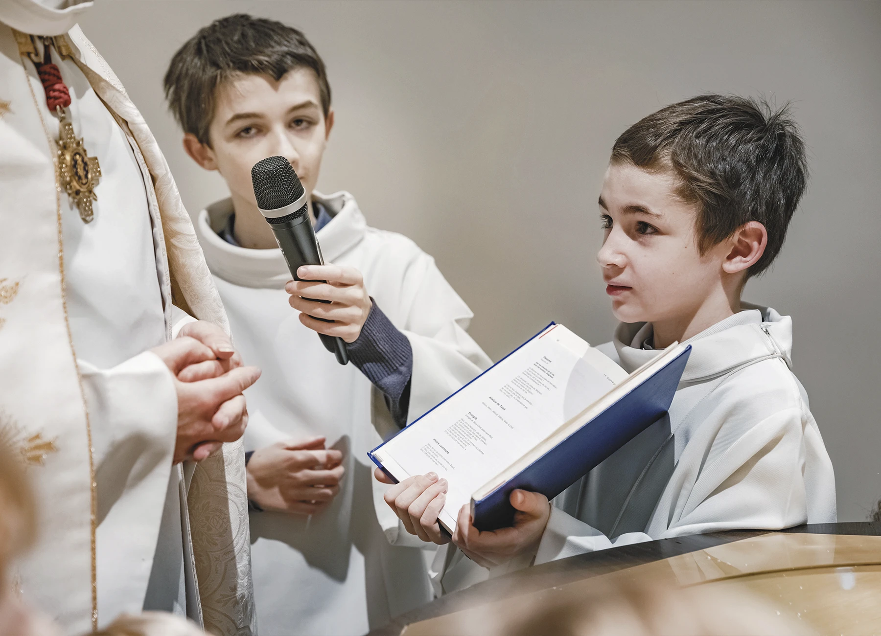 Un enfant de chœur tenant un livre de prières devant le prêtre durant la cérémonie