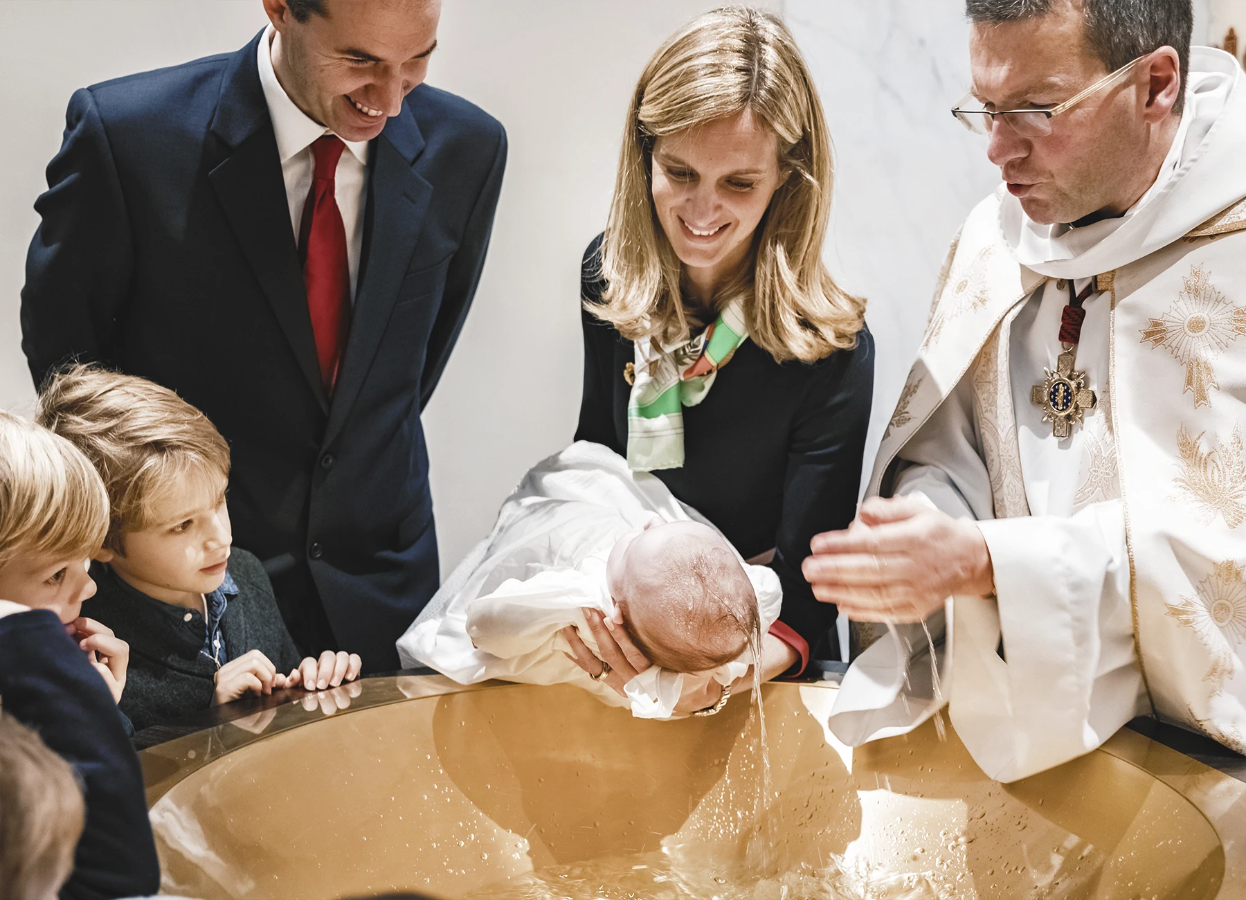 Le prêtre applique de l’eau sur la tête du deuxième bébé durant la cérémonie