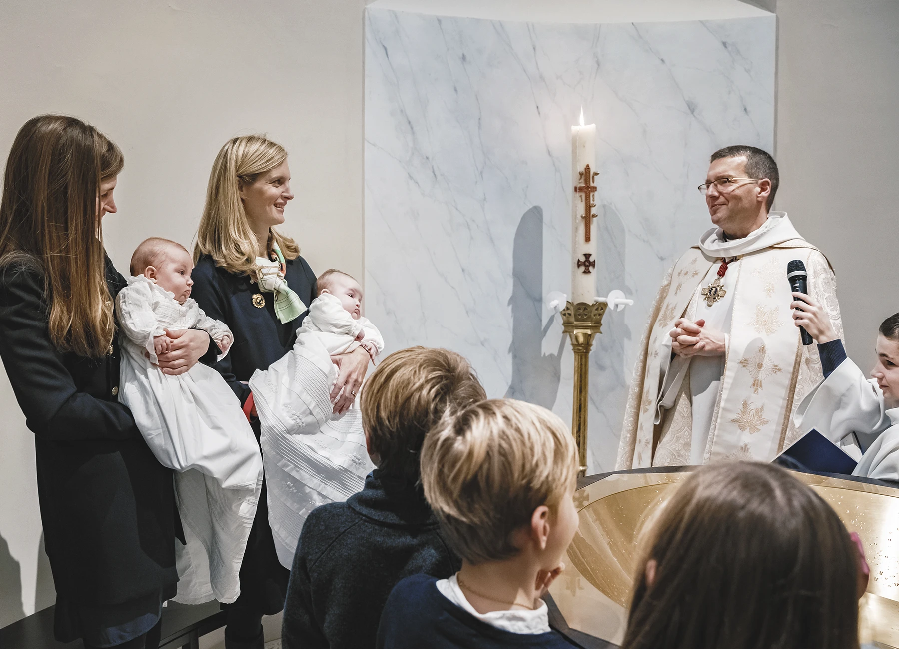 Les deux mères tenant leurs enfants dans leurs bras après le baptême.