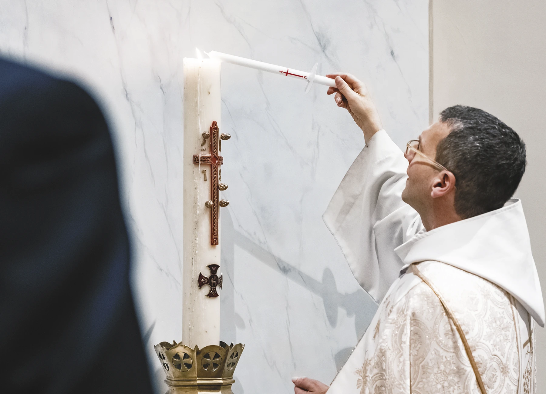 Le prêtre allume un cierge en signe de lumière et de foi