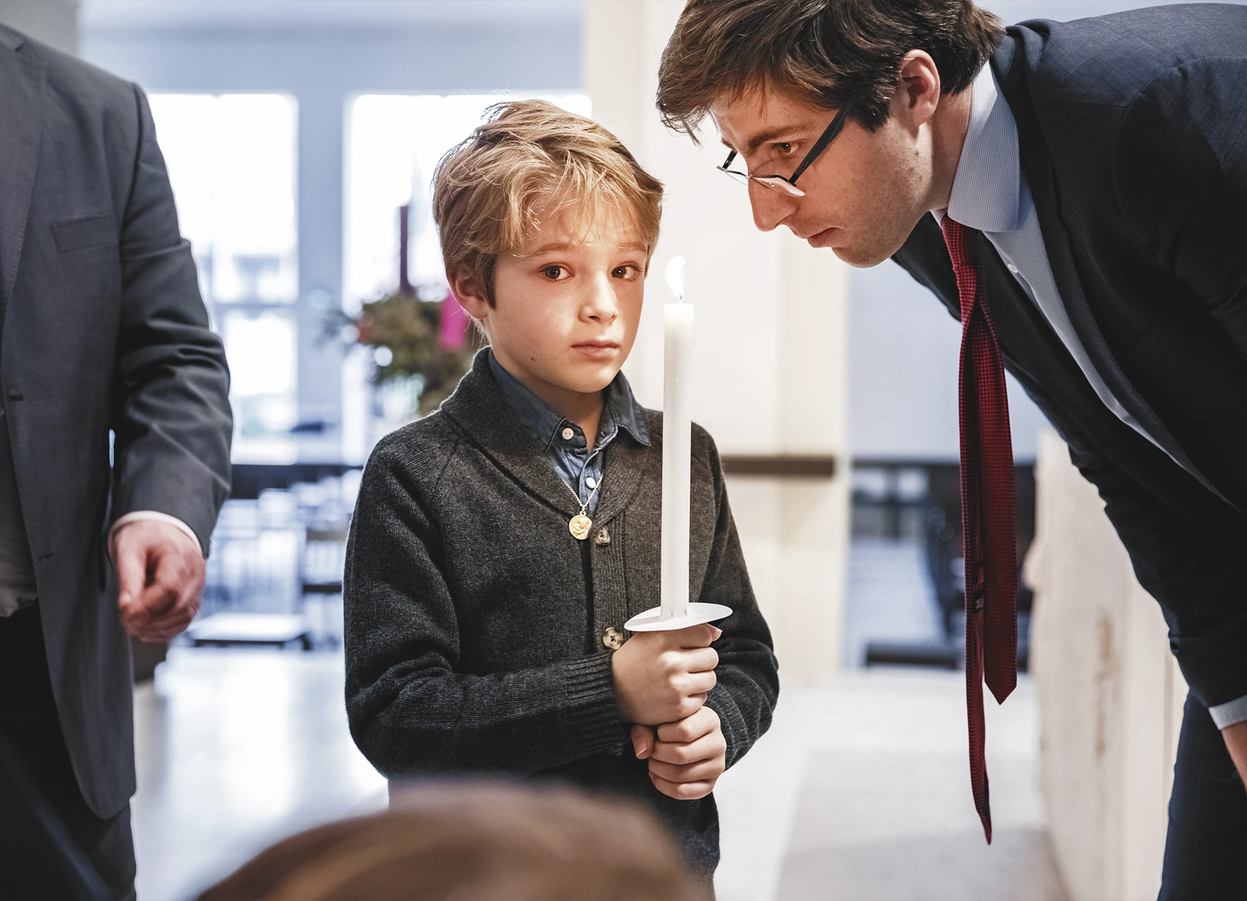 Un petit garçon tient une cierge allumée avec concentration