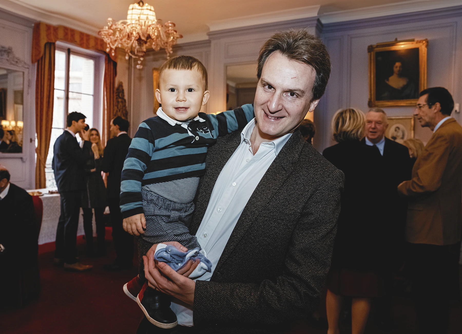 Un père tenant son jeune fils dans les bras durant la soirée.