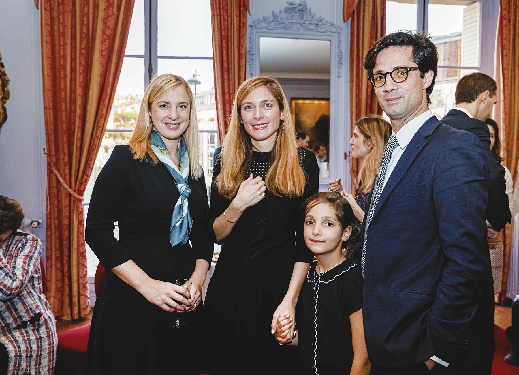 Groupe de quatre personnes, incluant un homme en costume bleu et une petite fille, dans un cadre familial