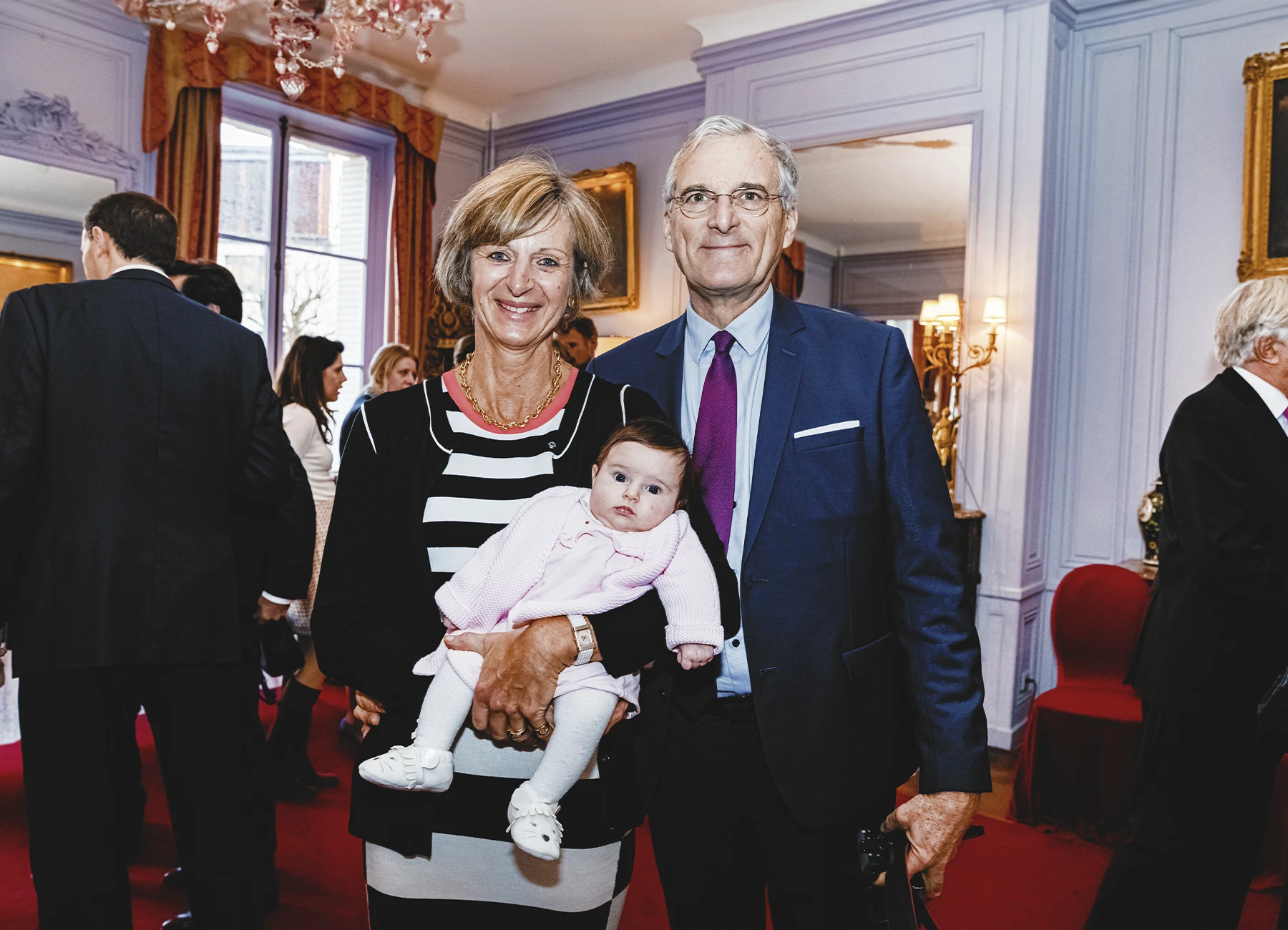 Une femme tenant un bébé dans ses bras, posant avec un homme lors de la soirée