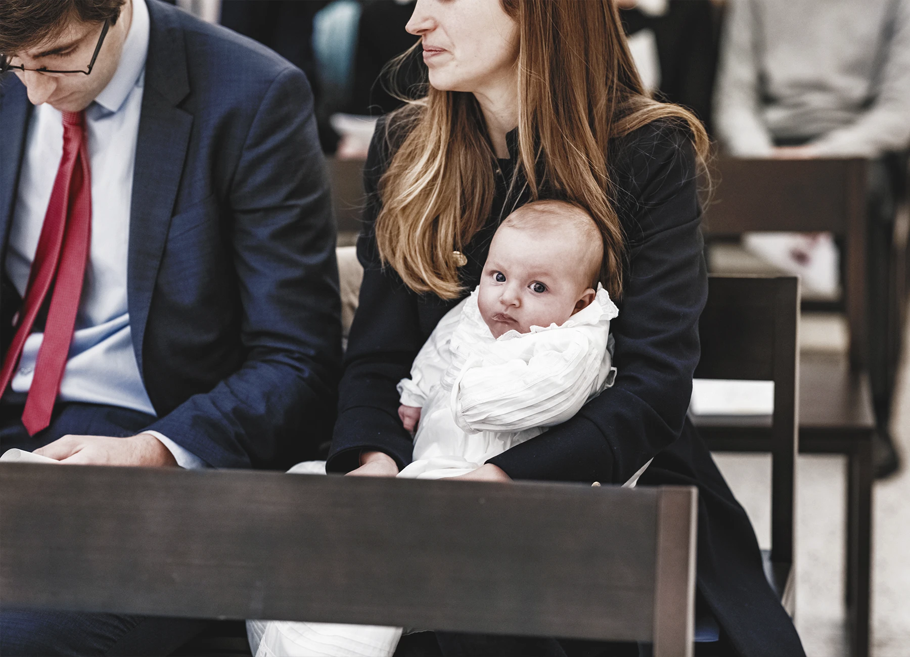 Une mère tenant son bébé dans ses bras dans l’église avant le début du baptême.