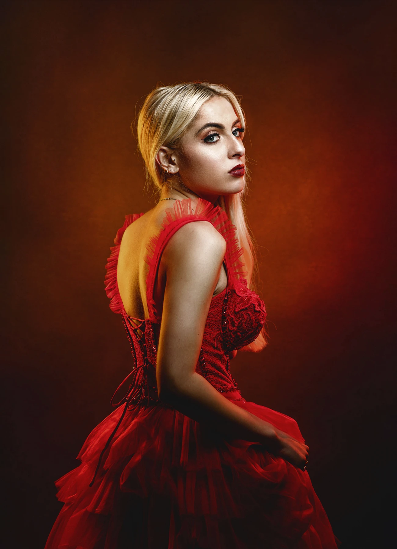 Candice vue de dos, visage tourné vers sa droite, dans une robe rouge en tulle