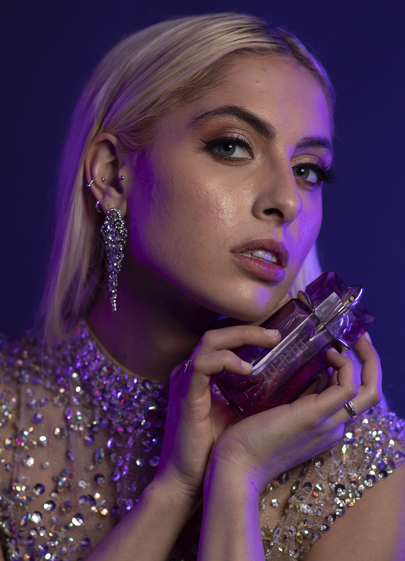 Photo Backstage avant traitement de Candice en plan serré, tenant un flacon de parfum Alien de Thierry Mugler