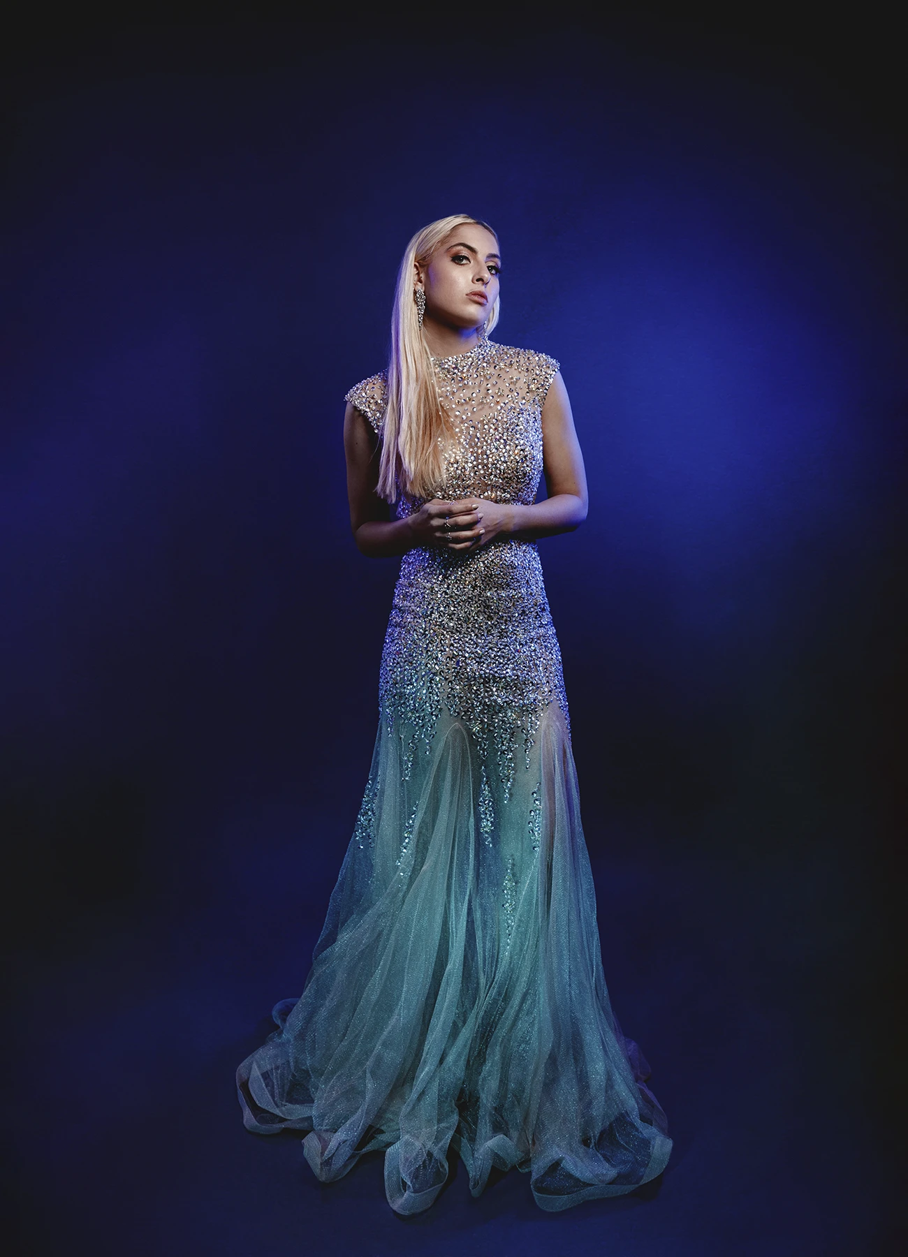 Candice debout dans une robe de soirée éclairée de lumières vertes et bleues