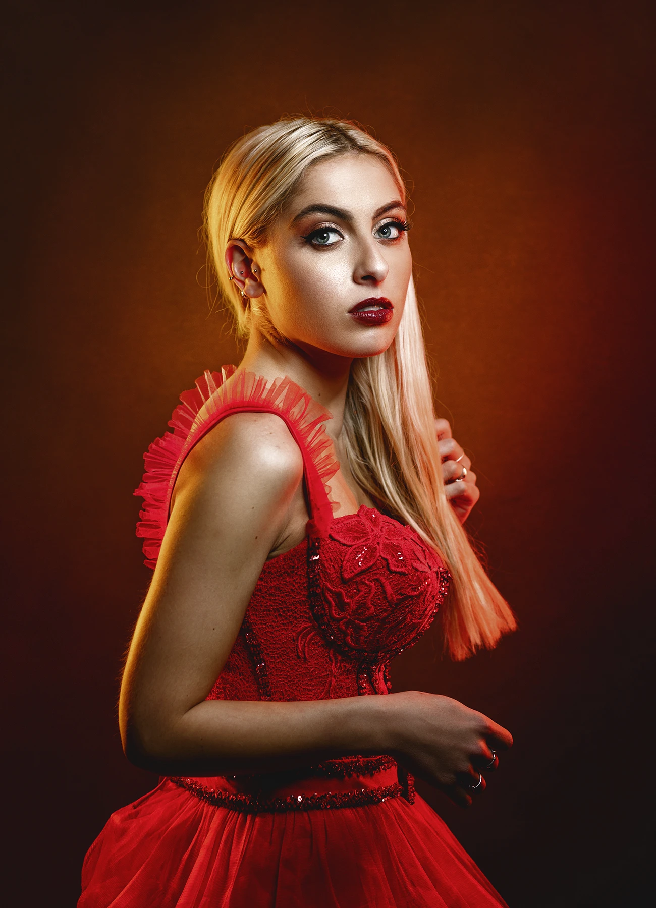 Portrait de Candice légèrement de profil, regardant la caméra, dans une robe de soirée en tulle rouge