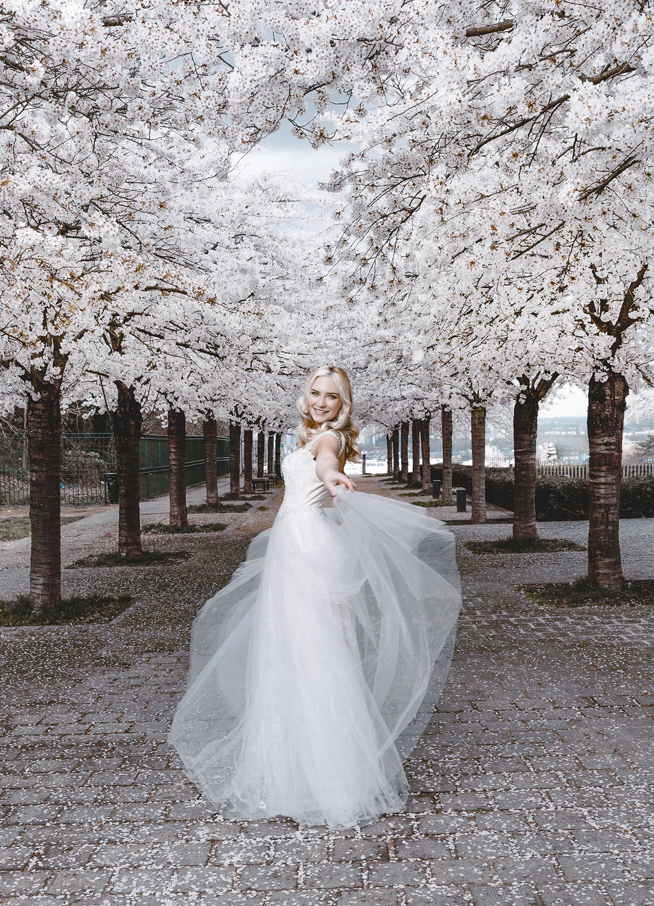 Eva Mikulski dans une robe de mariée en tulle, entourée de cerisiers en fleurs