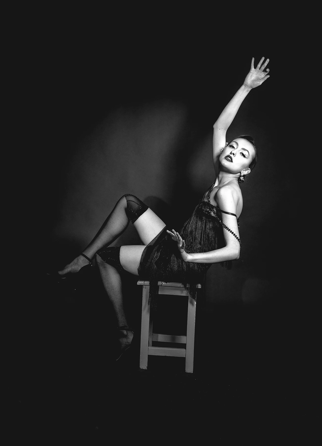 Kalysta en bas et robe style années 20, rendant hommage à Marlene Dietrich, assise sur un tabouret dans un studio, photographie réalisée par Laurène Zabary.