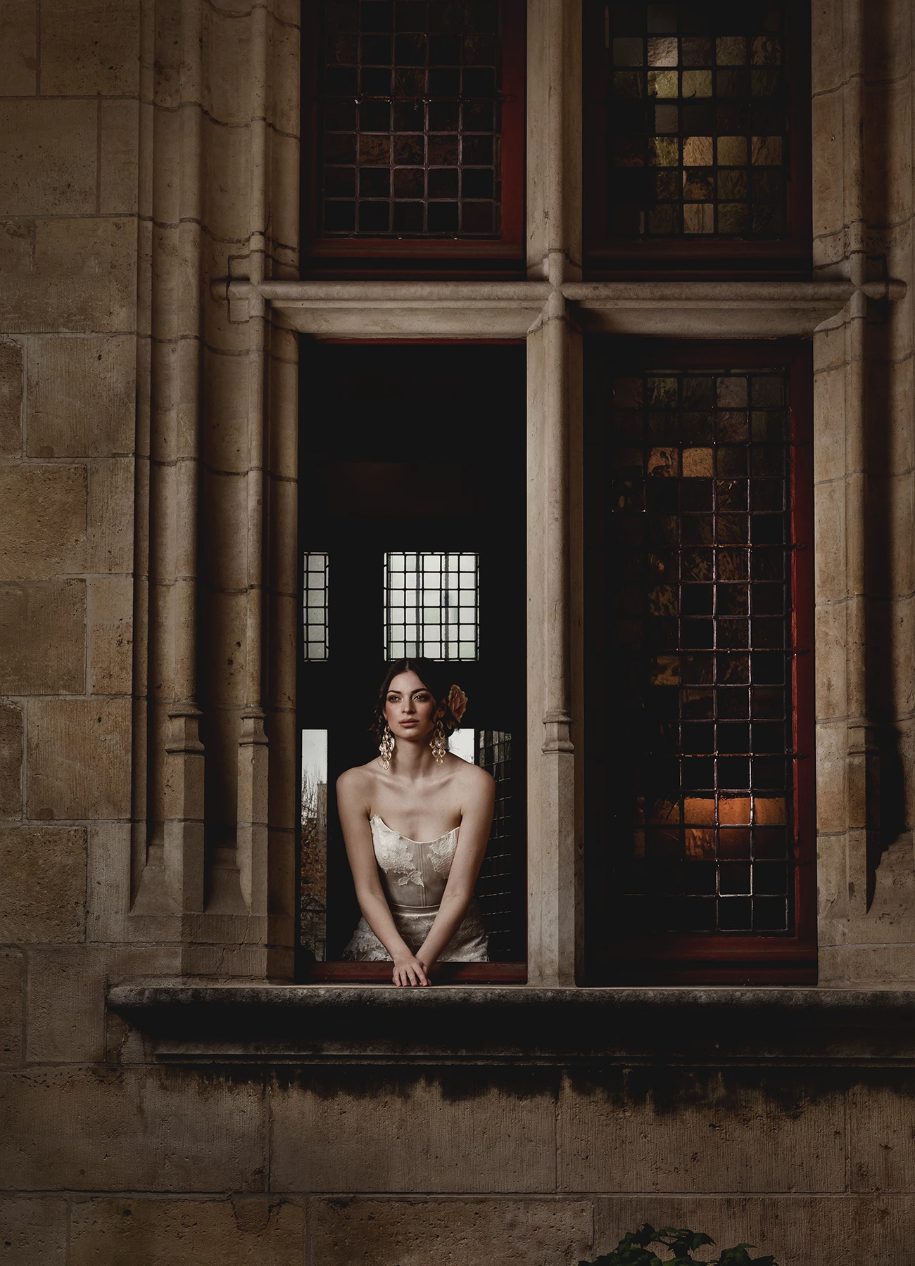 Susana en robe de mariée Elyssa Couture posant à une fenêtre de la bibliothèque Forney, photographie de mode en extérieur par Laurène Zabary.