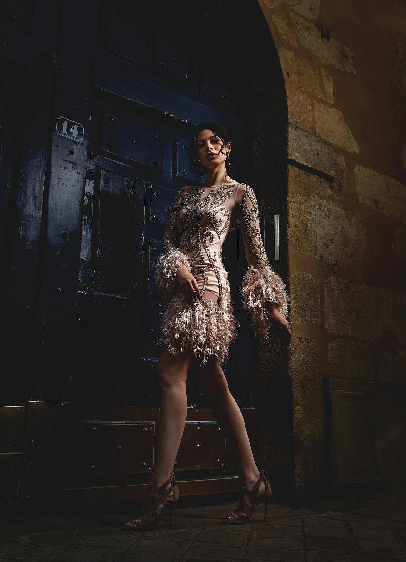 Modèle en robe Elyssa Couture capturée en contre-plongée, passant devant une porte en bois bleue, photographie de mode en extérieur par Laurène Zabary.