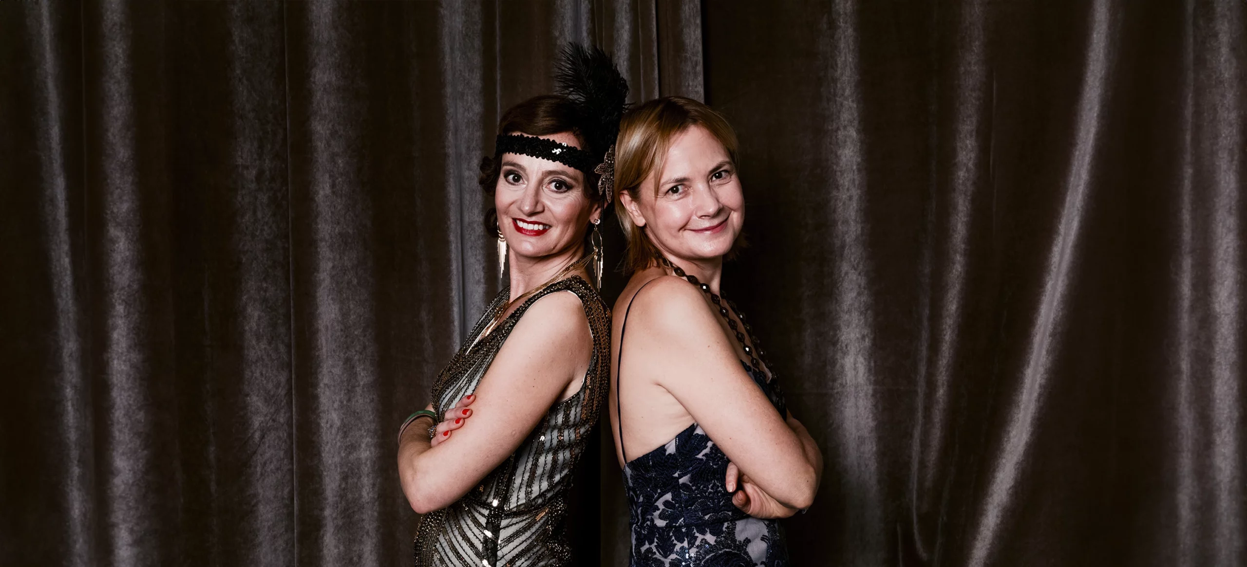 Portrait de deux femmes posant dos à dos en tenues des années 20 devant une draperie, réalisé lors d’une soirée d’anniversaire à l’hôtel Vernet par Laurène Zabary.