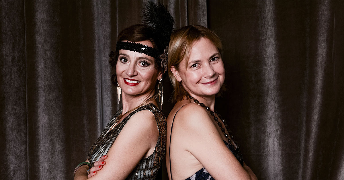 Portrait de deux femmes dos à dos en tenues des années 20 devant une draperie, réalisé lors d’une soirée d’anniversaire à l’hôtel Vernet par Laurène Zabary.