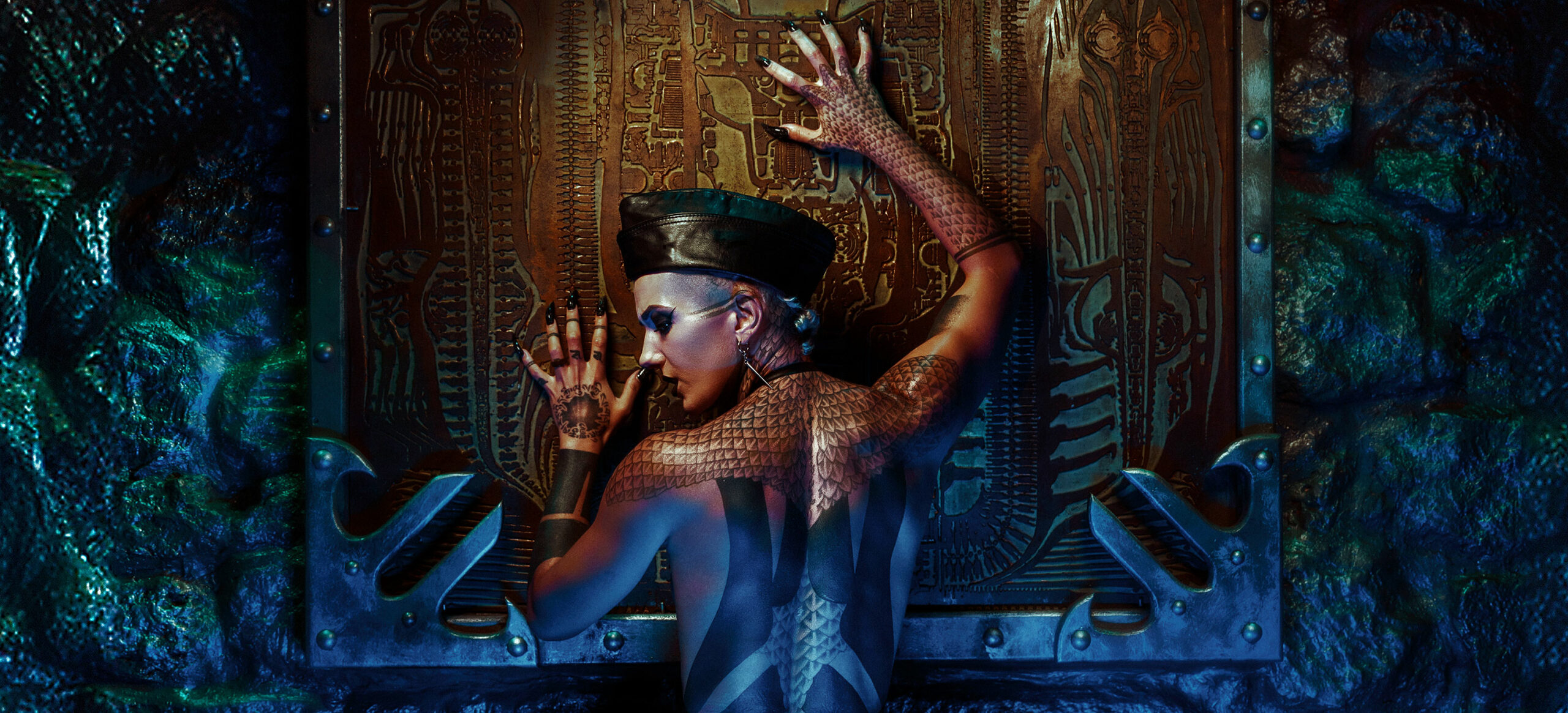 Léa Montravers de dos grattant l’œuvre de Giger sur le mur au bar BlackDog, vêtue d'un body noir minimaliste