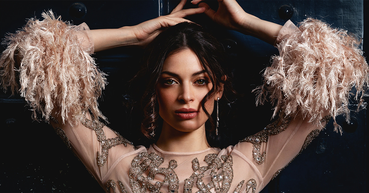 Modèle en robe de couturier appuyée contre une porte, photographie de mode prise en extérieur par Laurène Zabary.